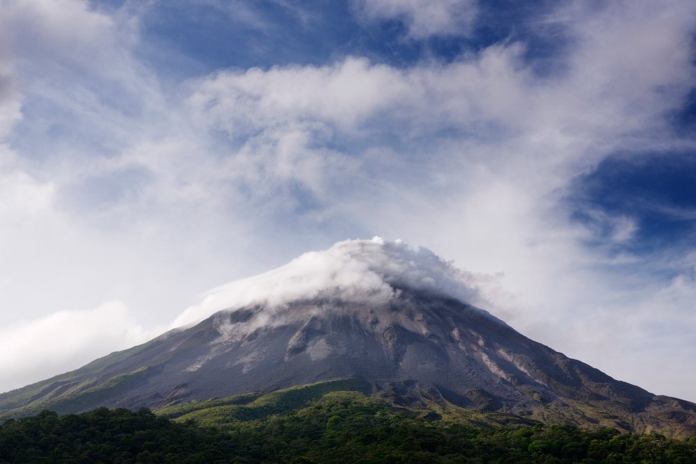Arenal volcano peak with clouds over forested slopes