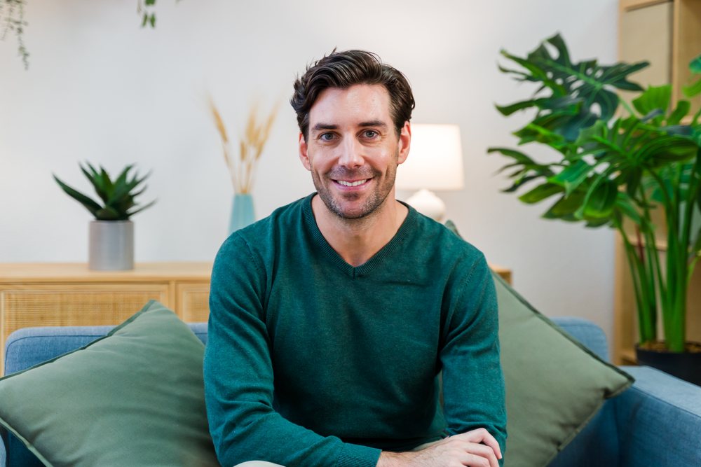 White man smiling seated on sofa in modern living room