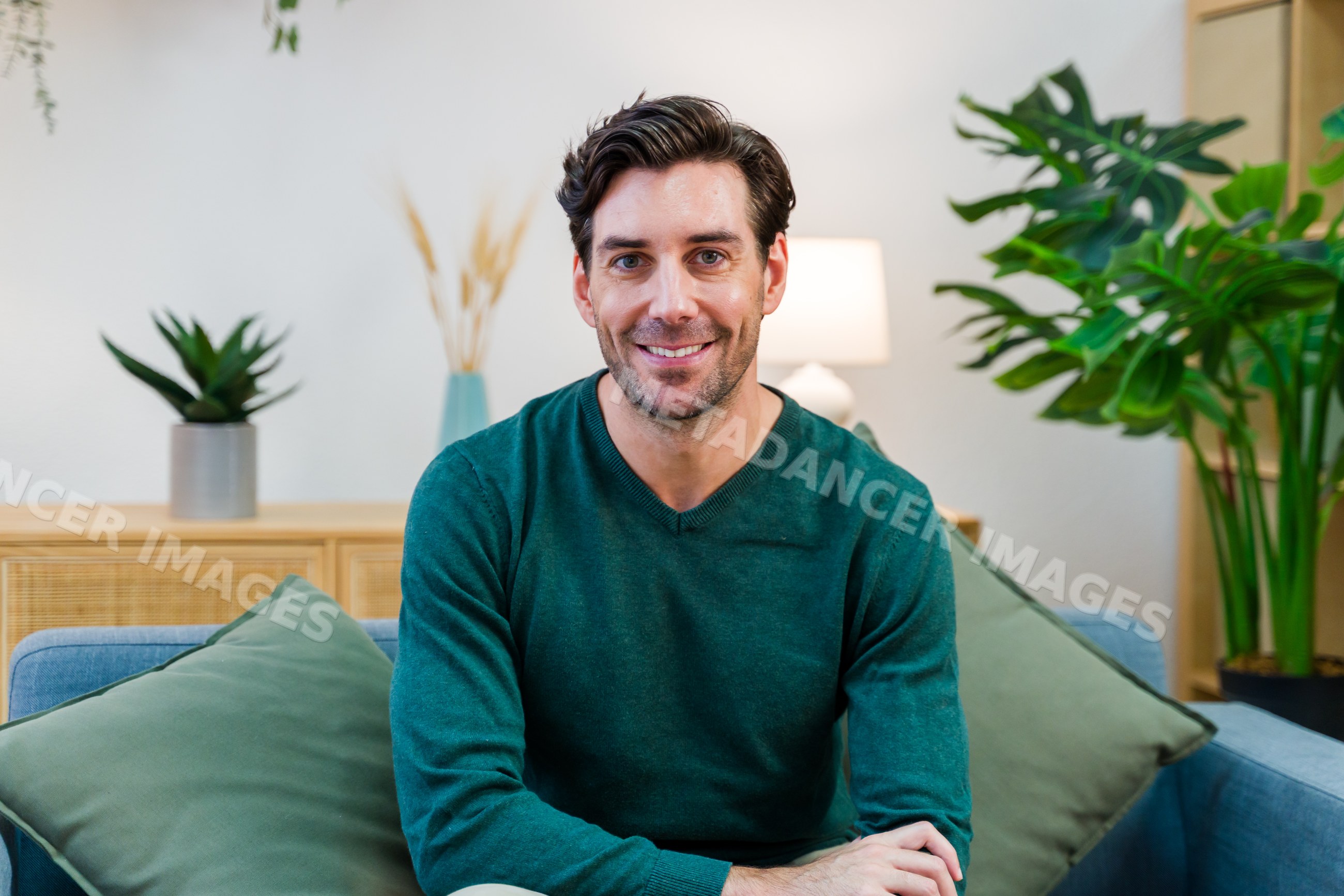 White man smiling seated on sofa in modern living room