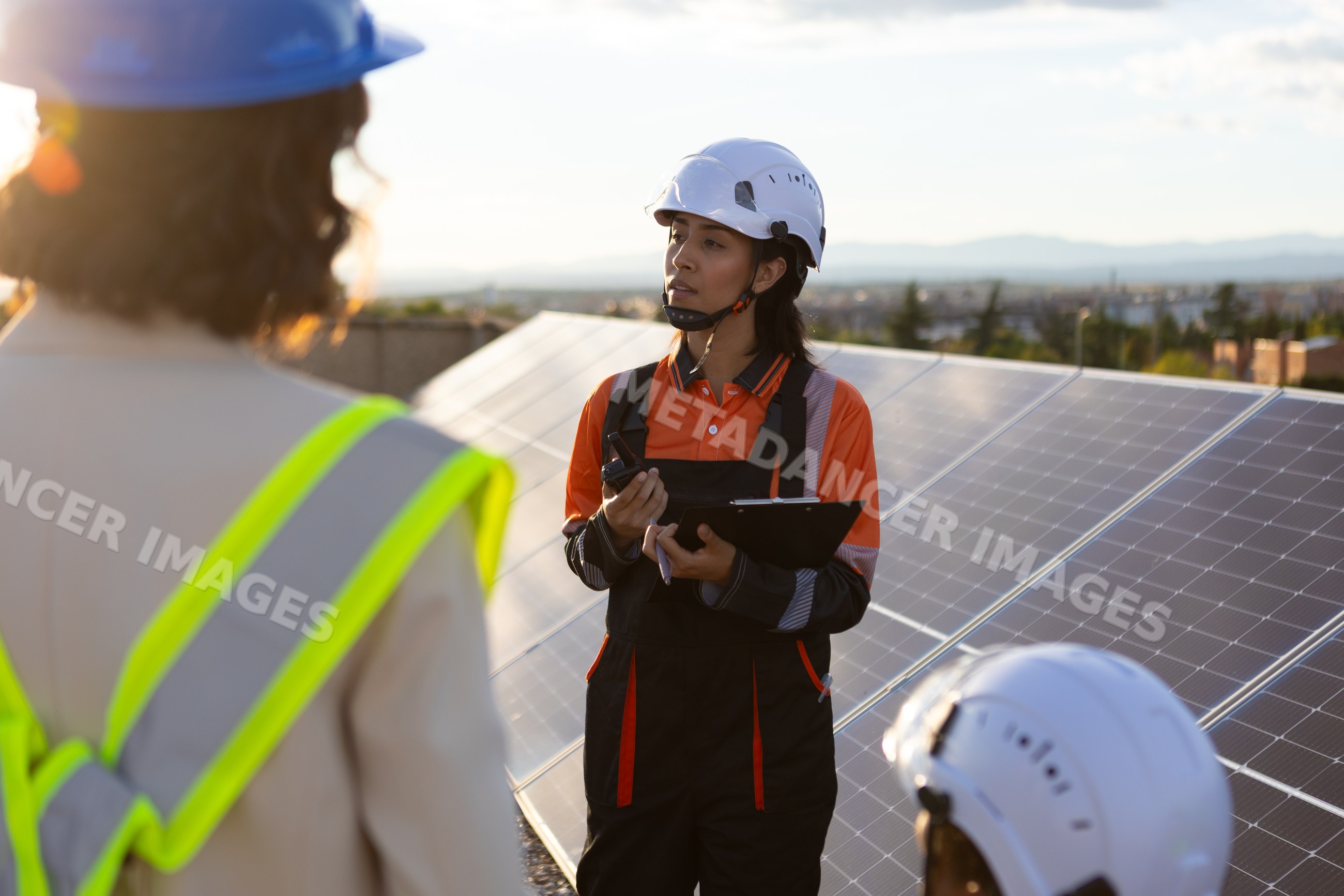 Female engineer inspecting solar panels outdoors at sunset in Madrid