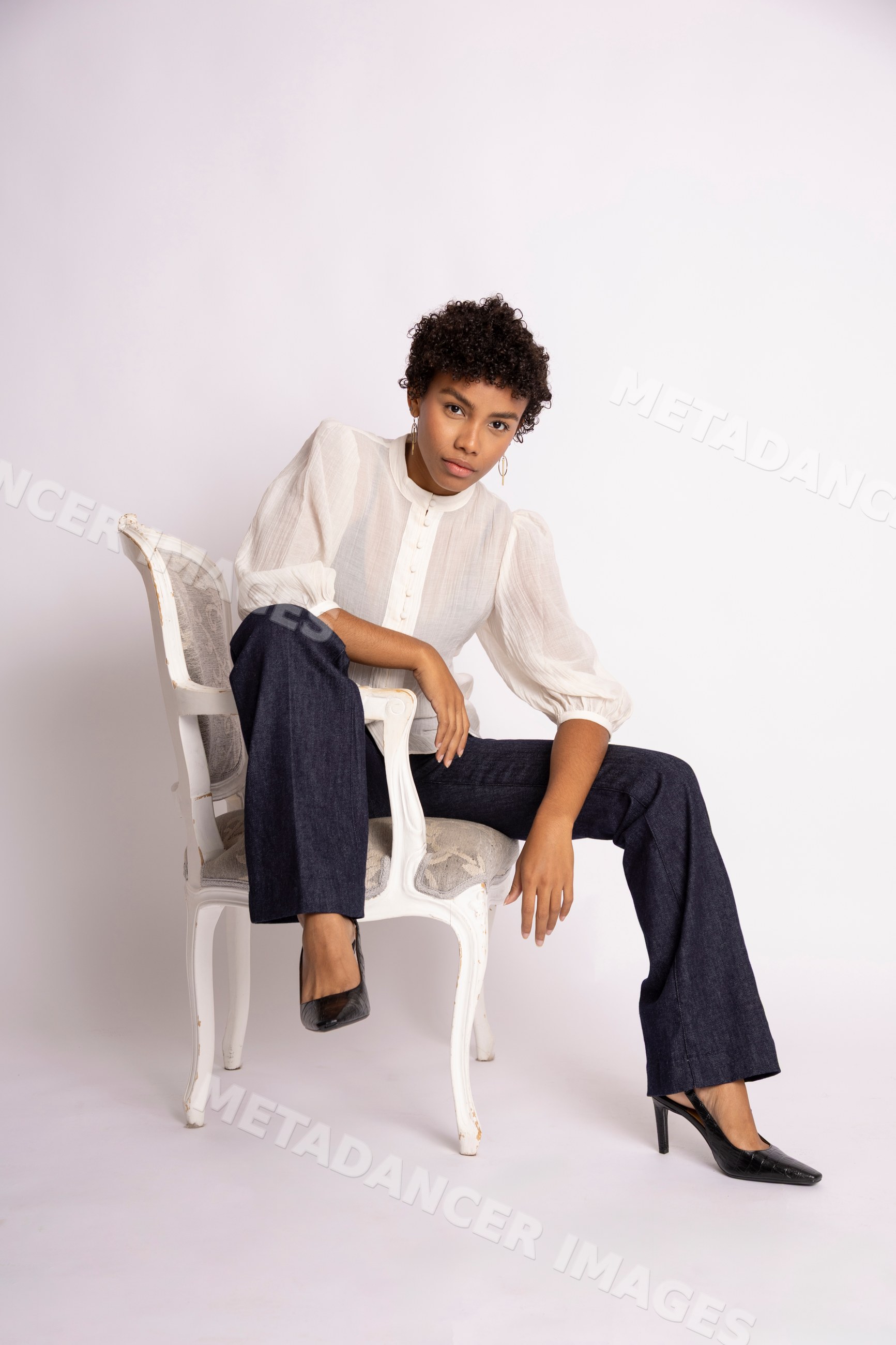 Hispanic woman seated on white chair wearing puff sleeve blouse