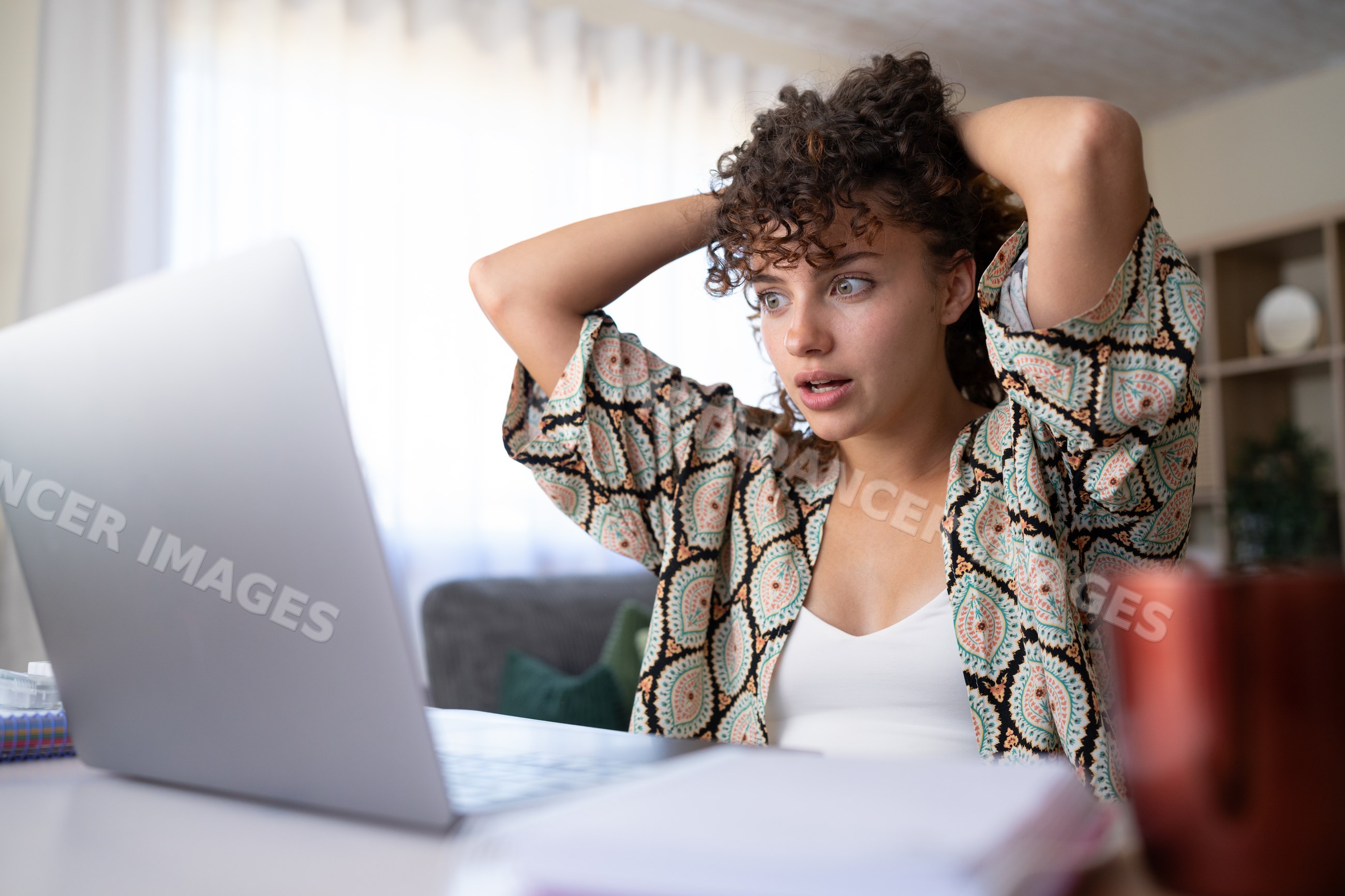 Shocked white woman using laptop at home desk in Spain
