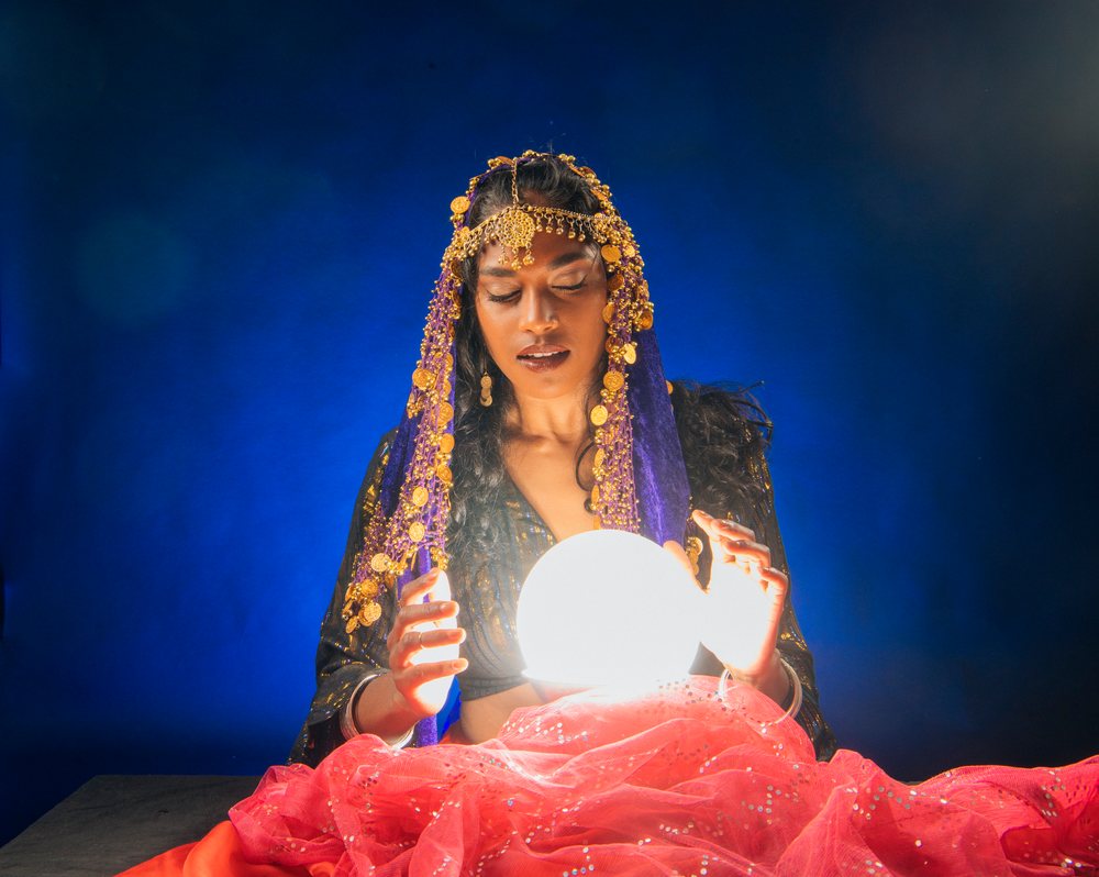A fortune teller looks into a glowing crystal ball with mystic focus