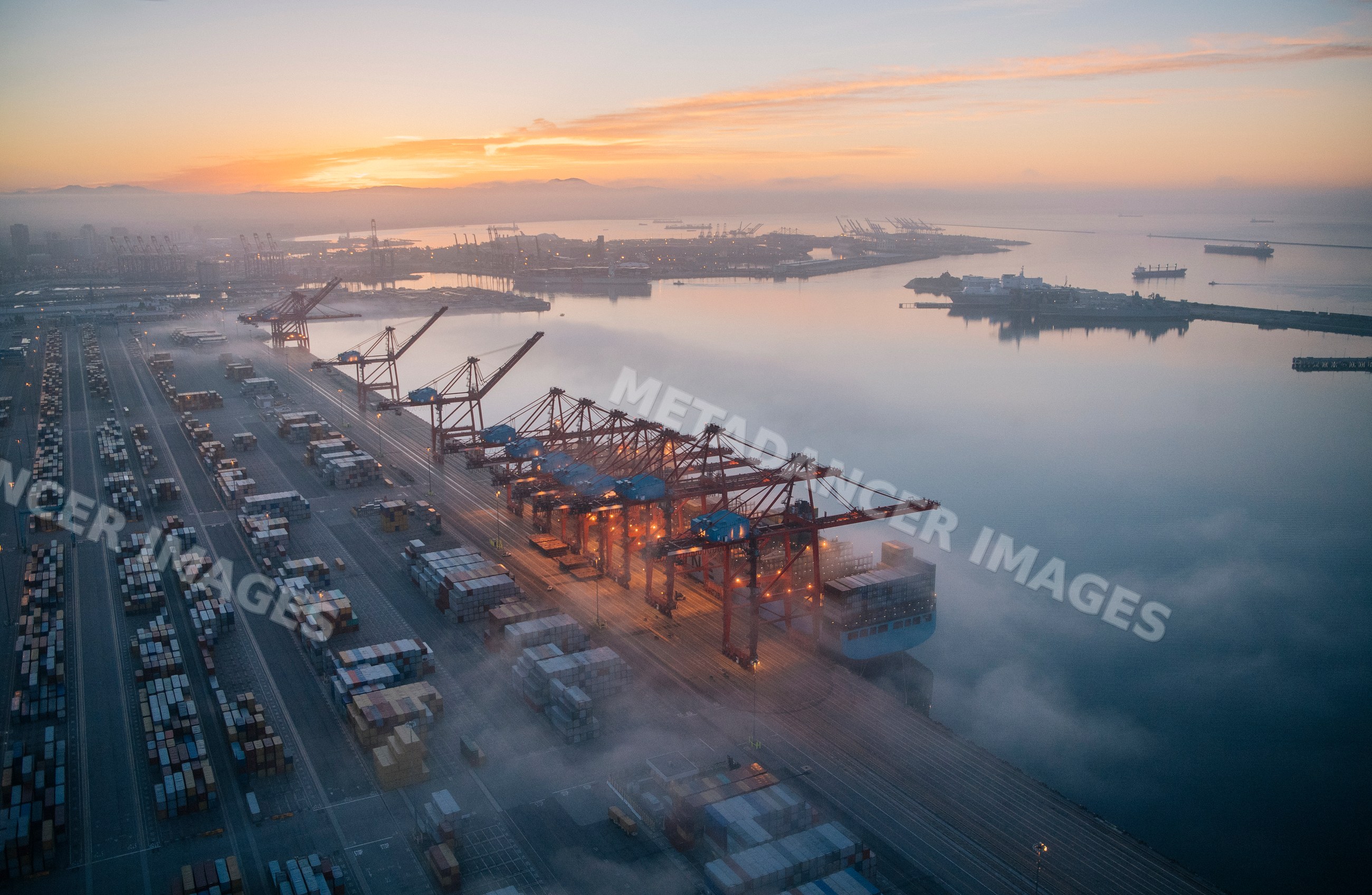 Container port with cranes loading cargo at sunrise in Long Beach