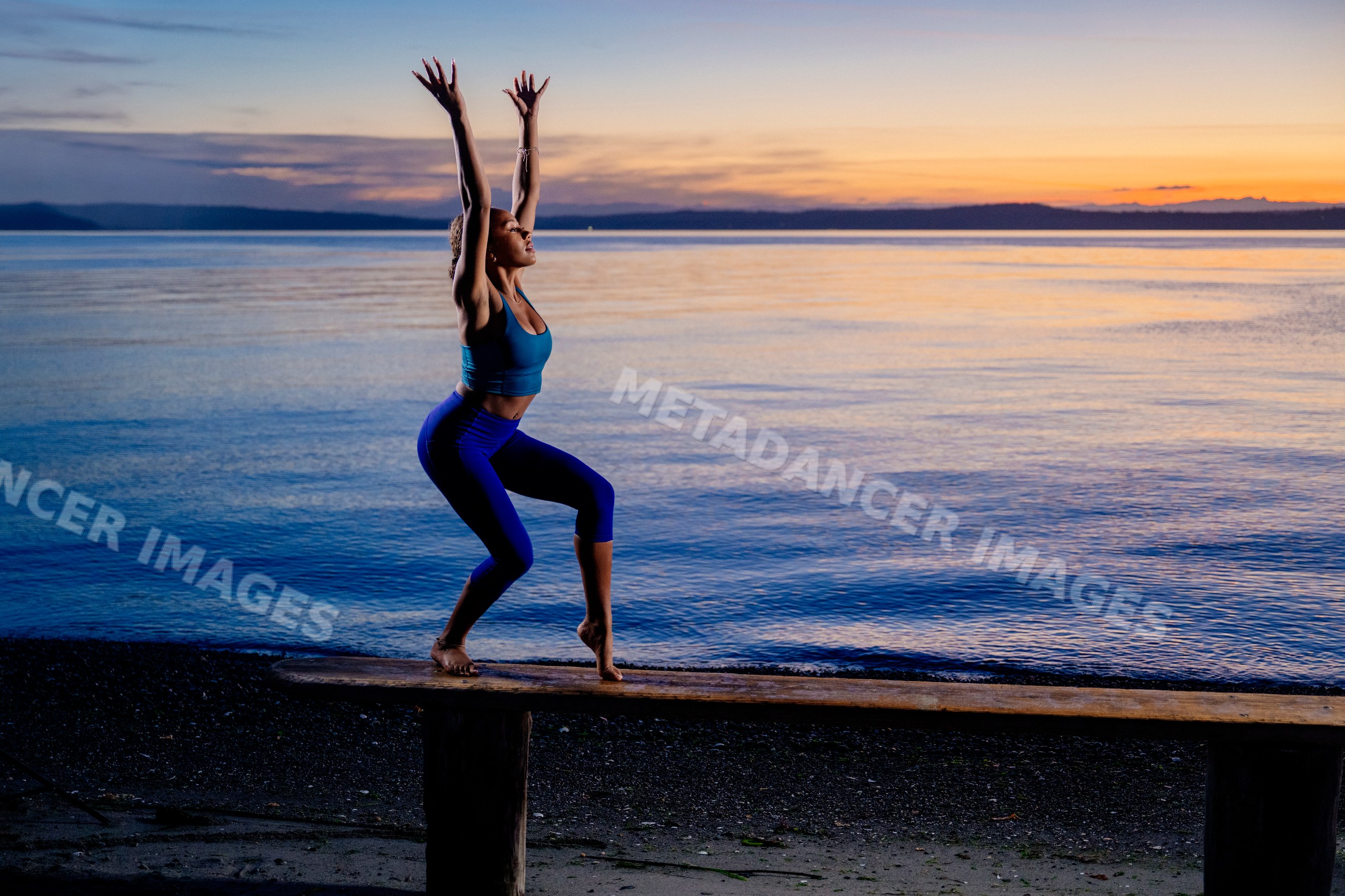 Hispanic woman practicing yoga balancing pose on bench by lake