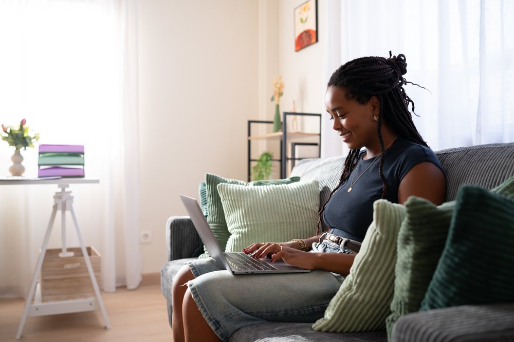 African American woman sitting on a sofa typing on her laptop