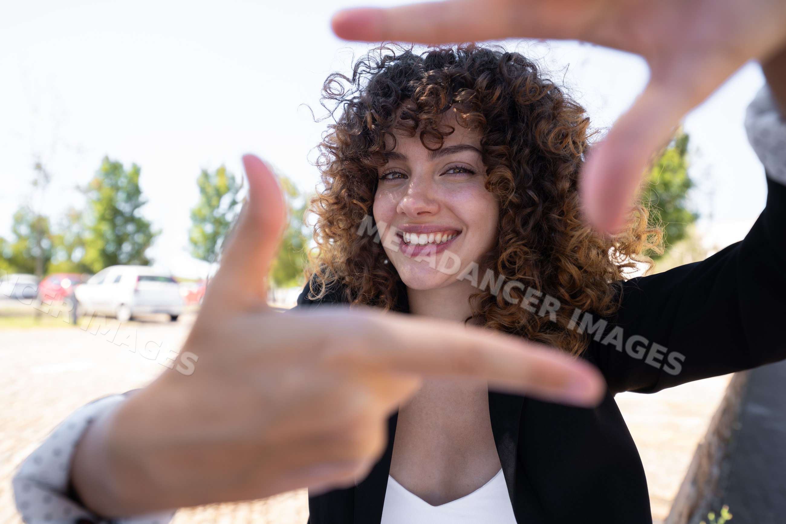 Smiling white woman with curly hair outdoors in a park