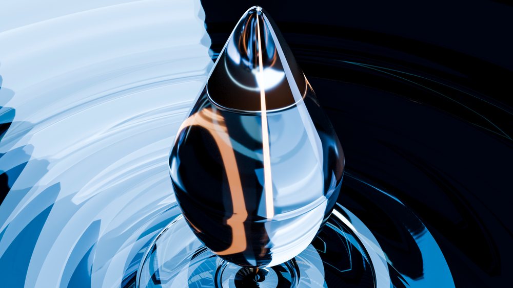 Close-up of a water drop creating ripples on a reflective surface