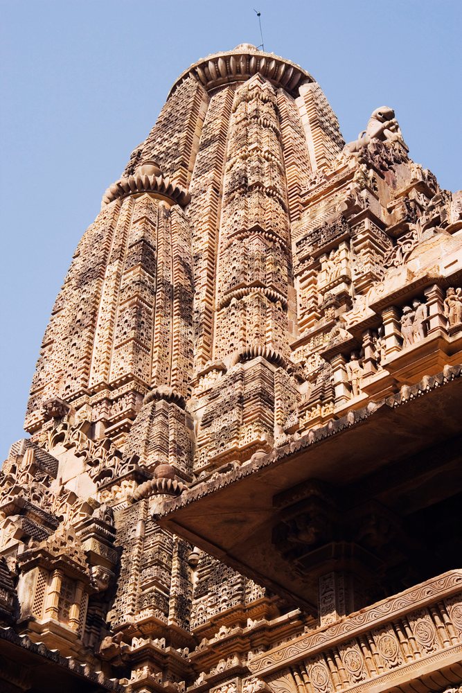 Khajuraho temple tower with intricate ancient stone carvings, india