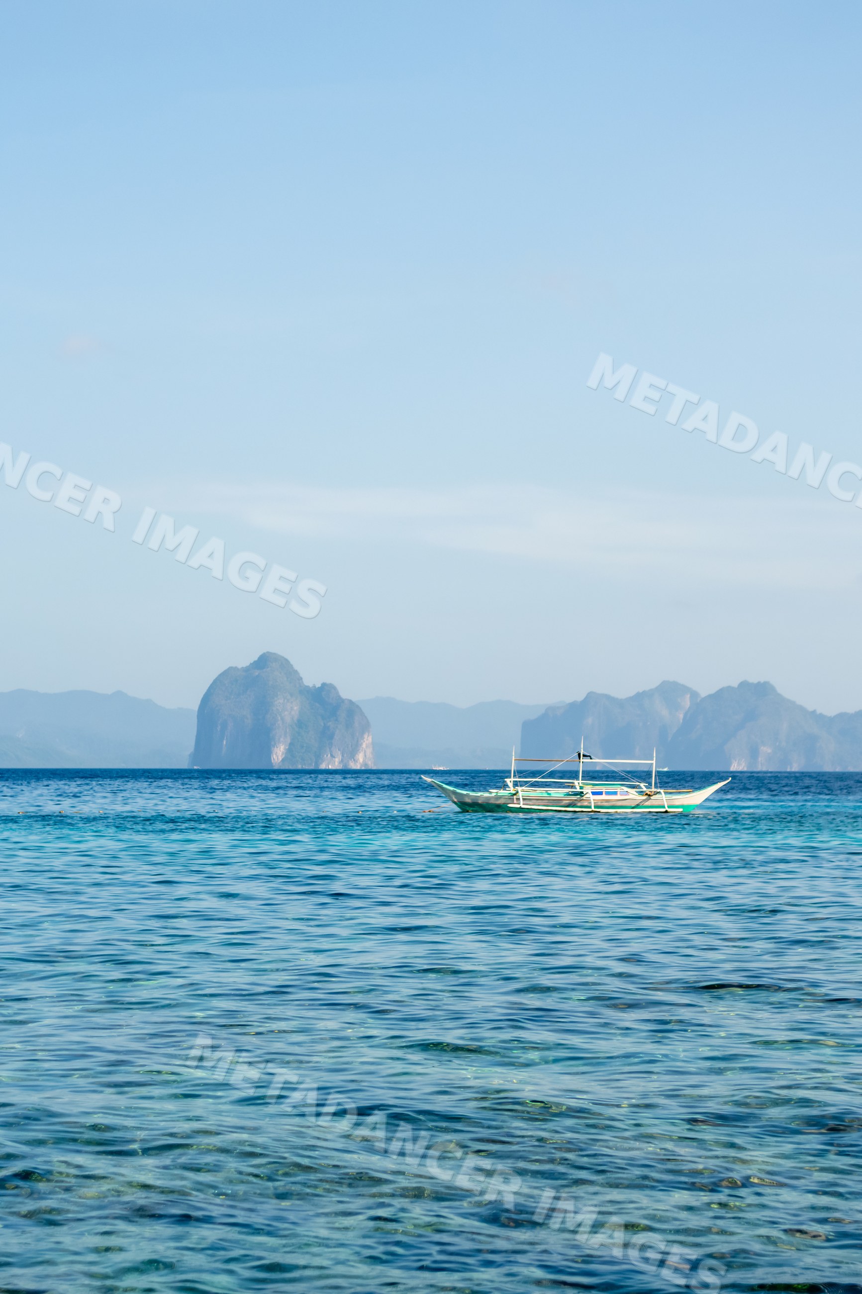 Boat on clear blue ocean near islands in the Philippines