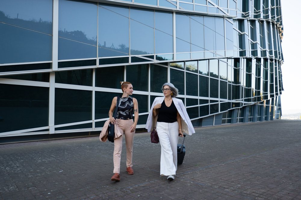 Businesswomen walking and talking outside modern glass building