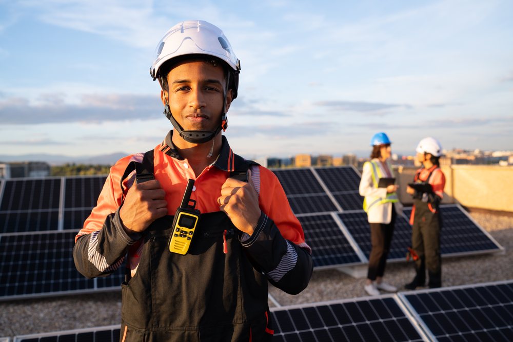 Hispanic and white worker with walkie talkie on rooftop solar panel