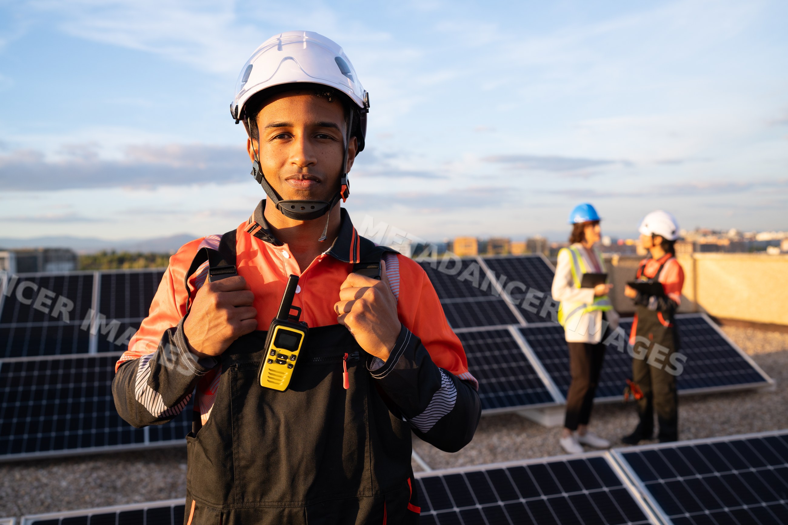 Hispanic and white worker with walkie talkie on rooftop solar panel