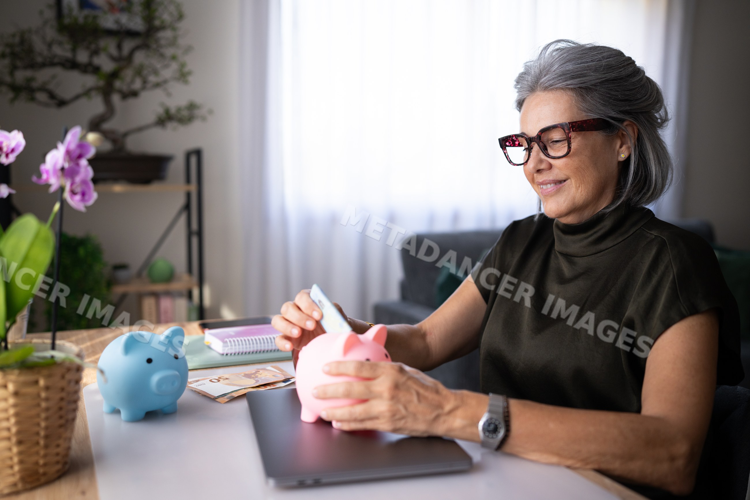 White woman saving money in piggy bank at home interior in Spain