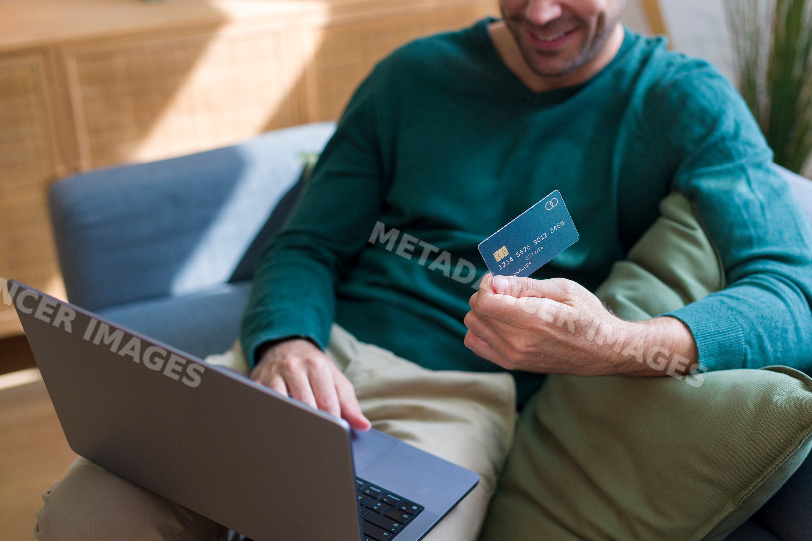 White man using laptop and credit card at home