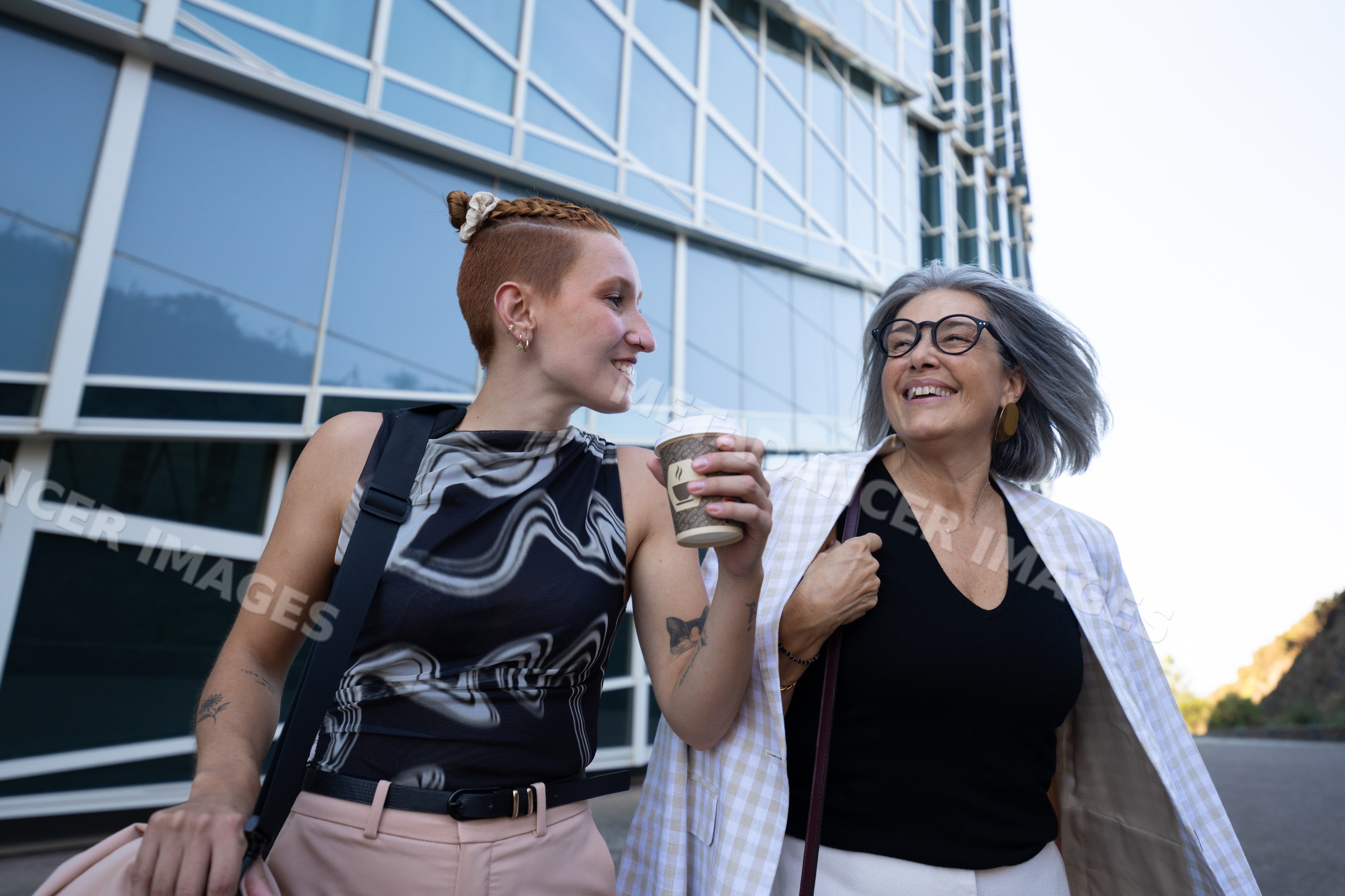 Two businesswomen walking and talking outside modern office building