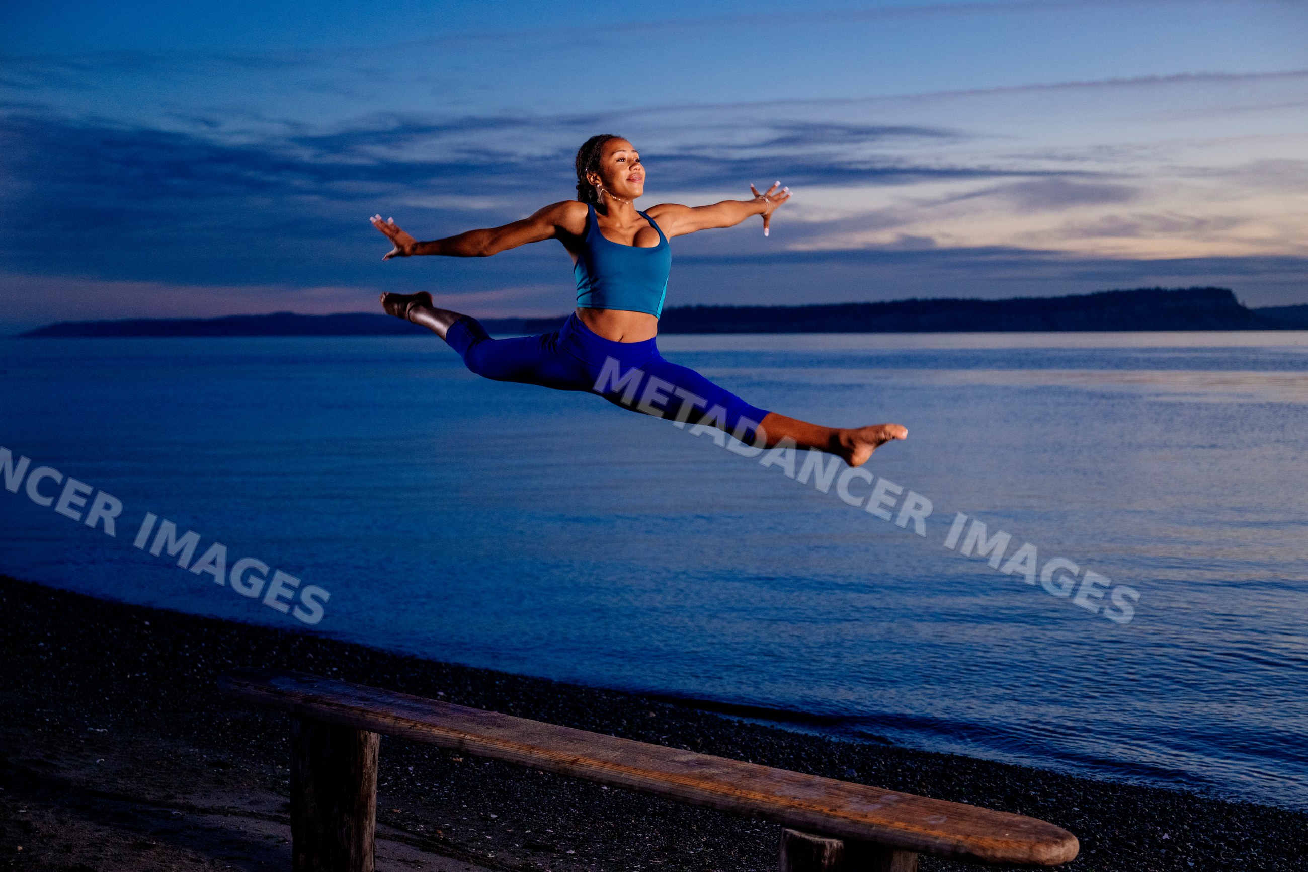 Hispanic woman leaping in acrobatic jump on beach at sunset in the USA