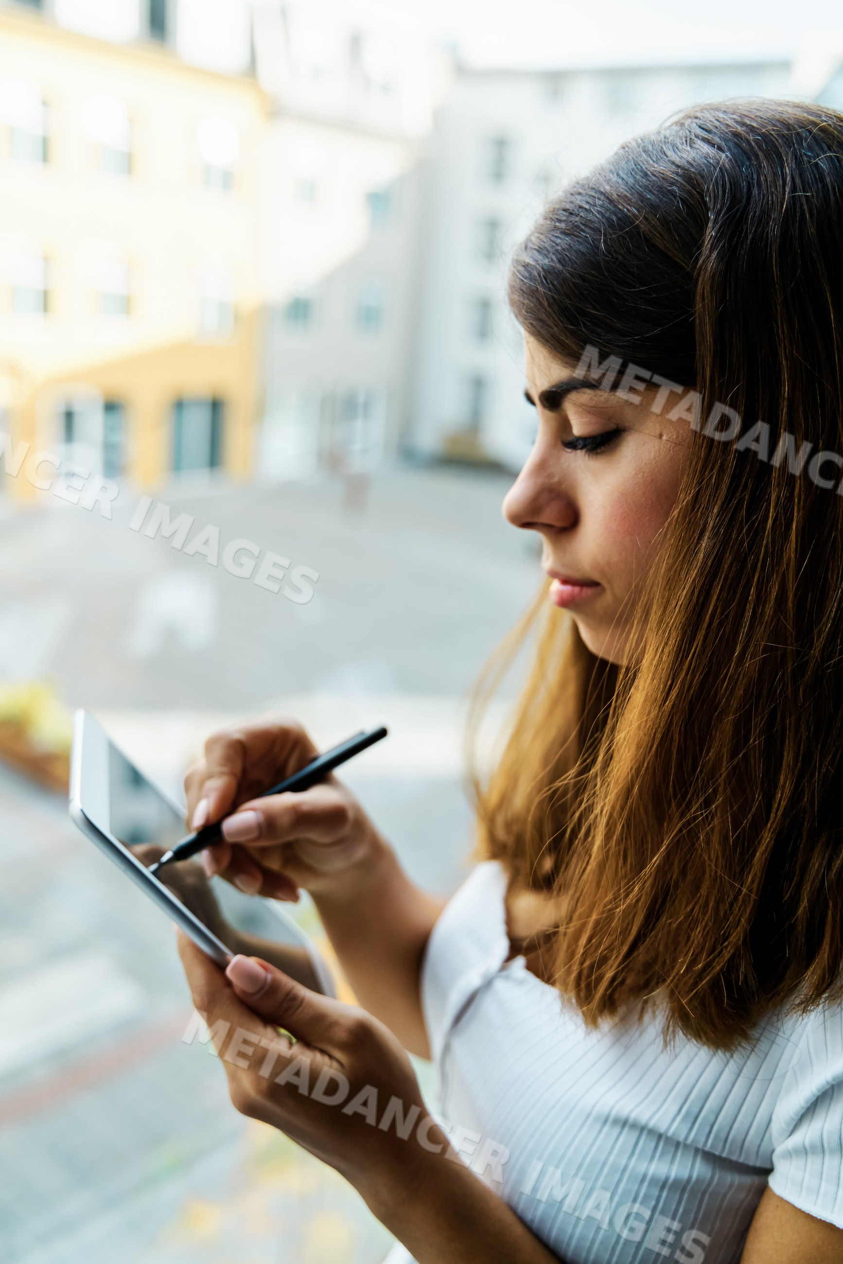 A woman uses a stylus pen on a tablet indoors in a hotel