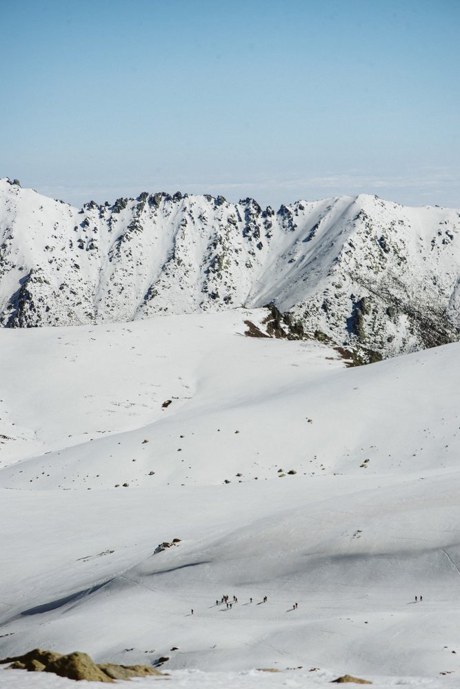 Mountaineering group hiking snowy mountains with rocky peaks