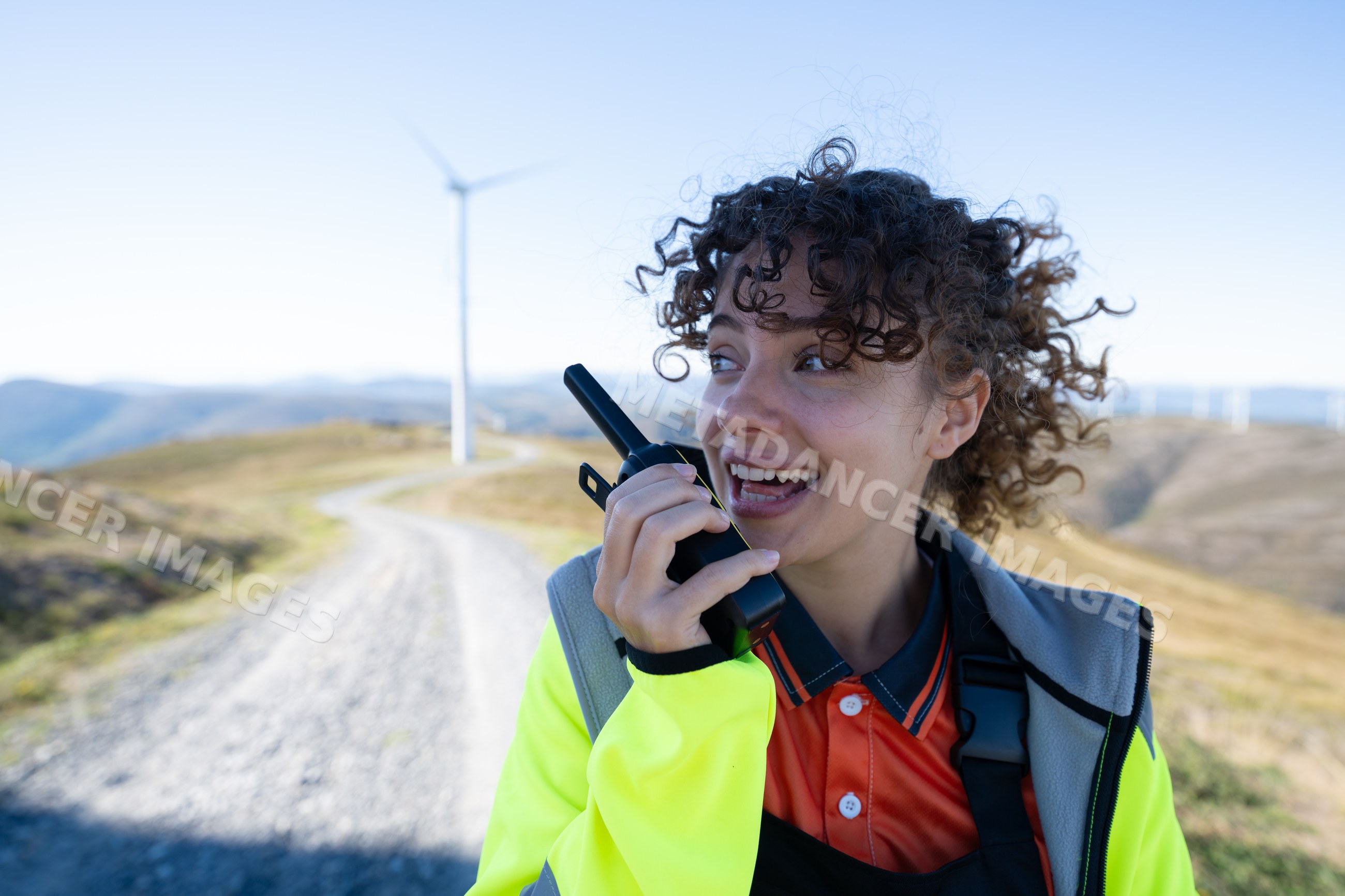 White woman using walkie talkie near wind turbines in Galicia