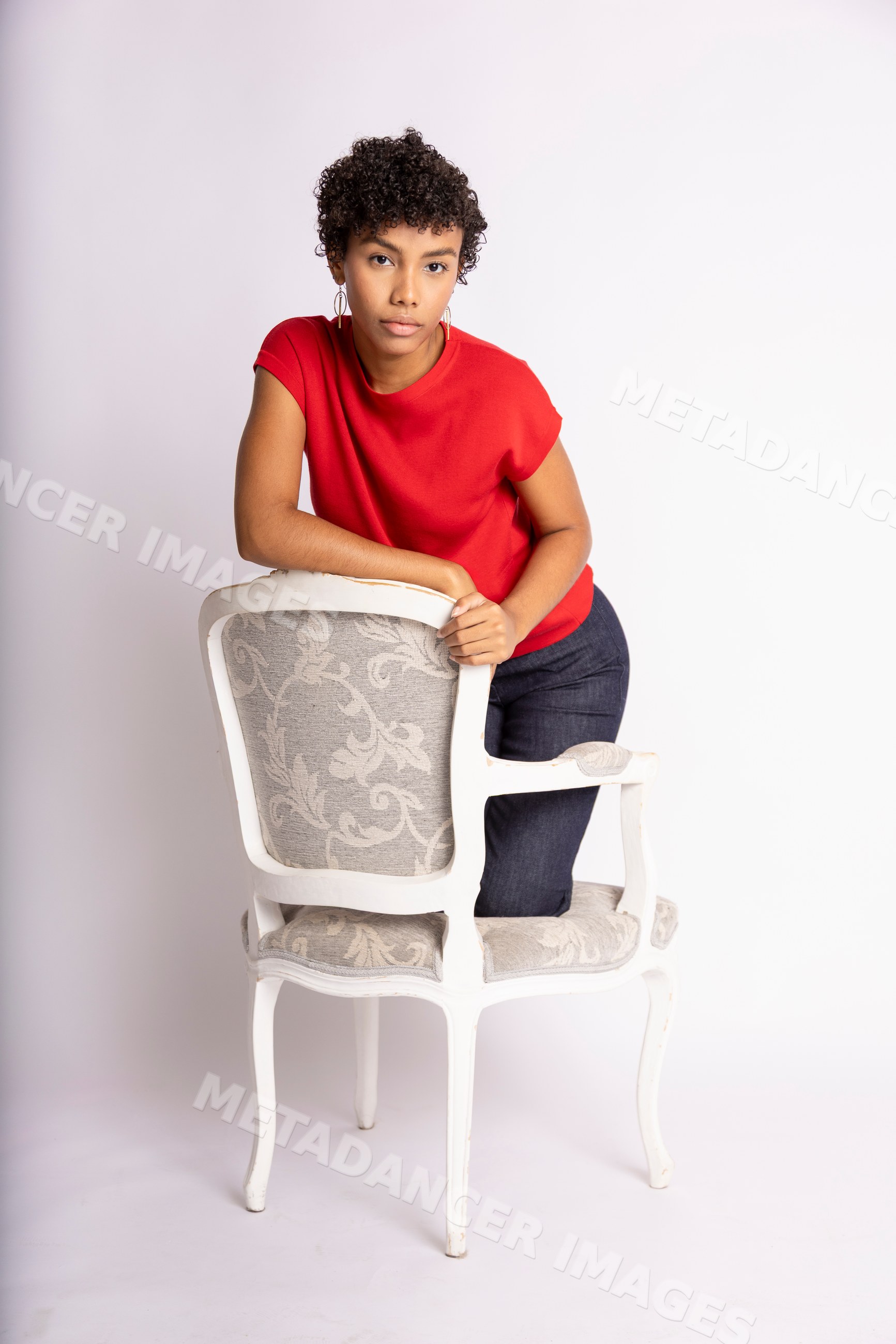 Hispanic woman leaning on a vintage upholstered chair