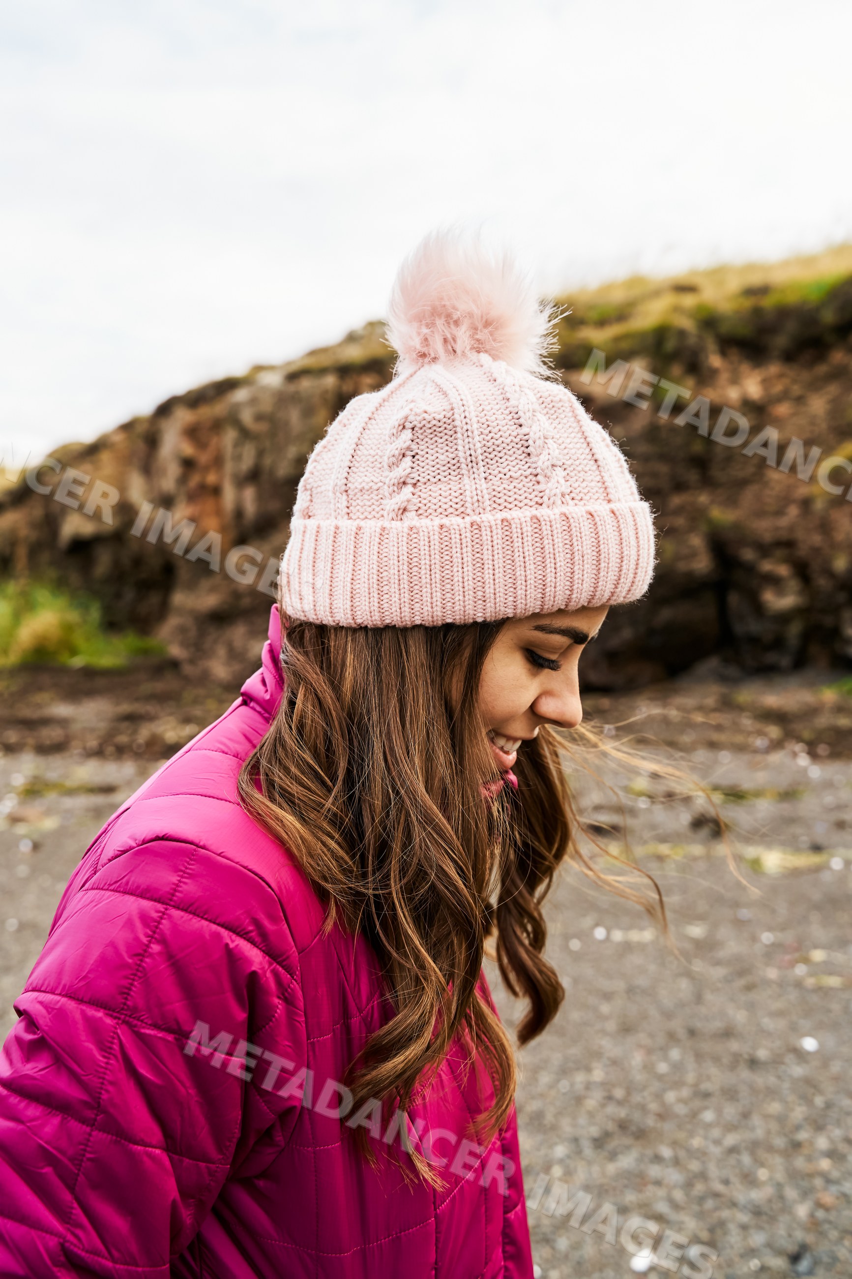 A white woman smiles outside wearing a pink hat and jacket