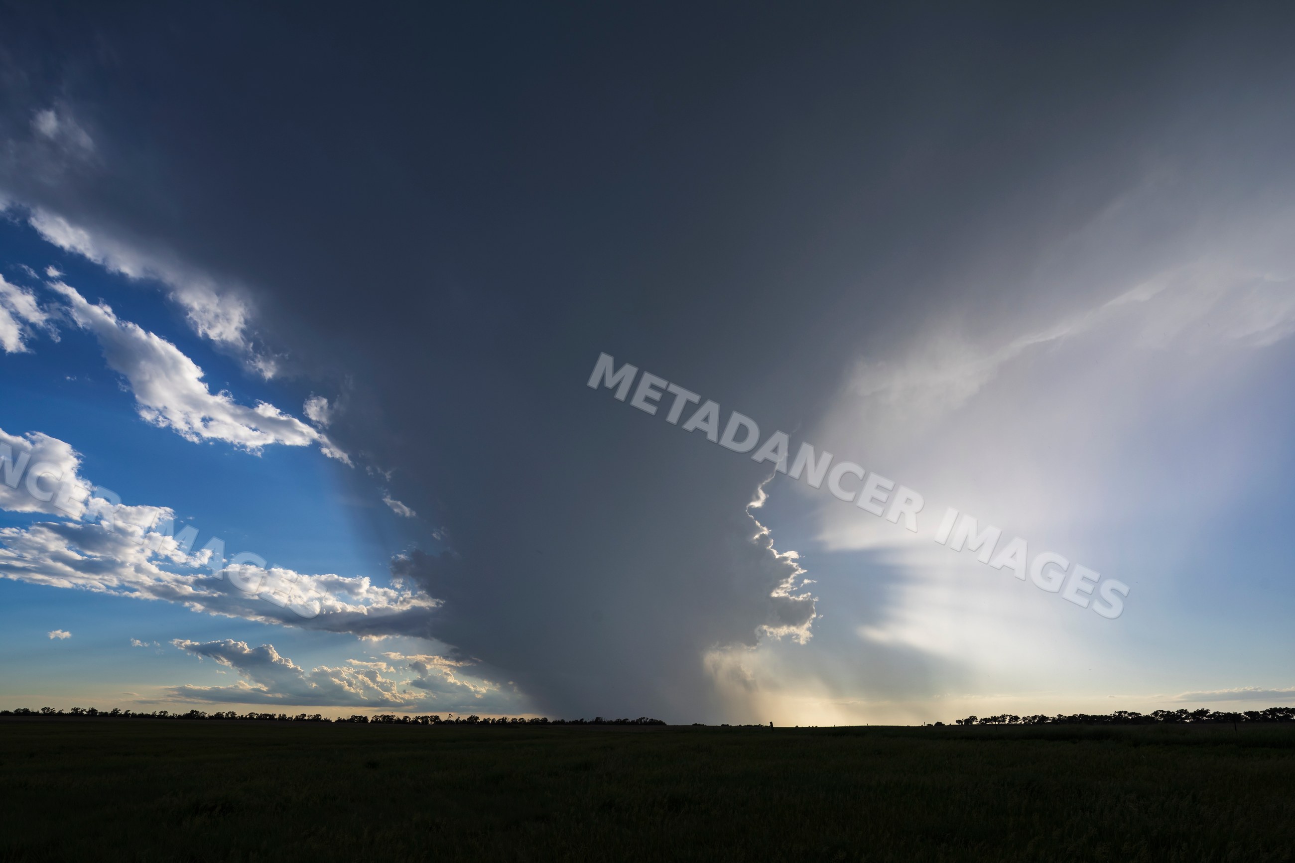 Storm with dark clouds and sunlight over flat field