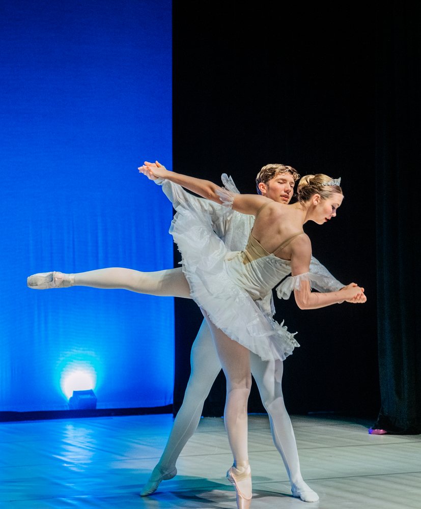 Ballet dancers perform a pas de deux on stage during a dance