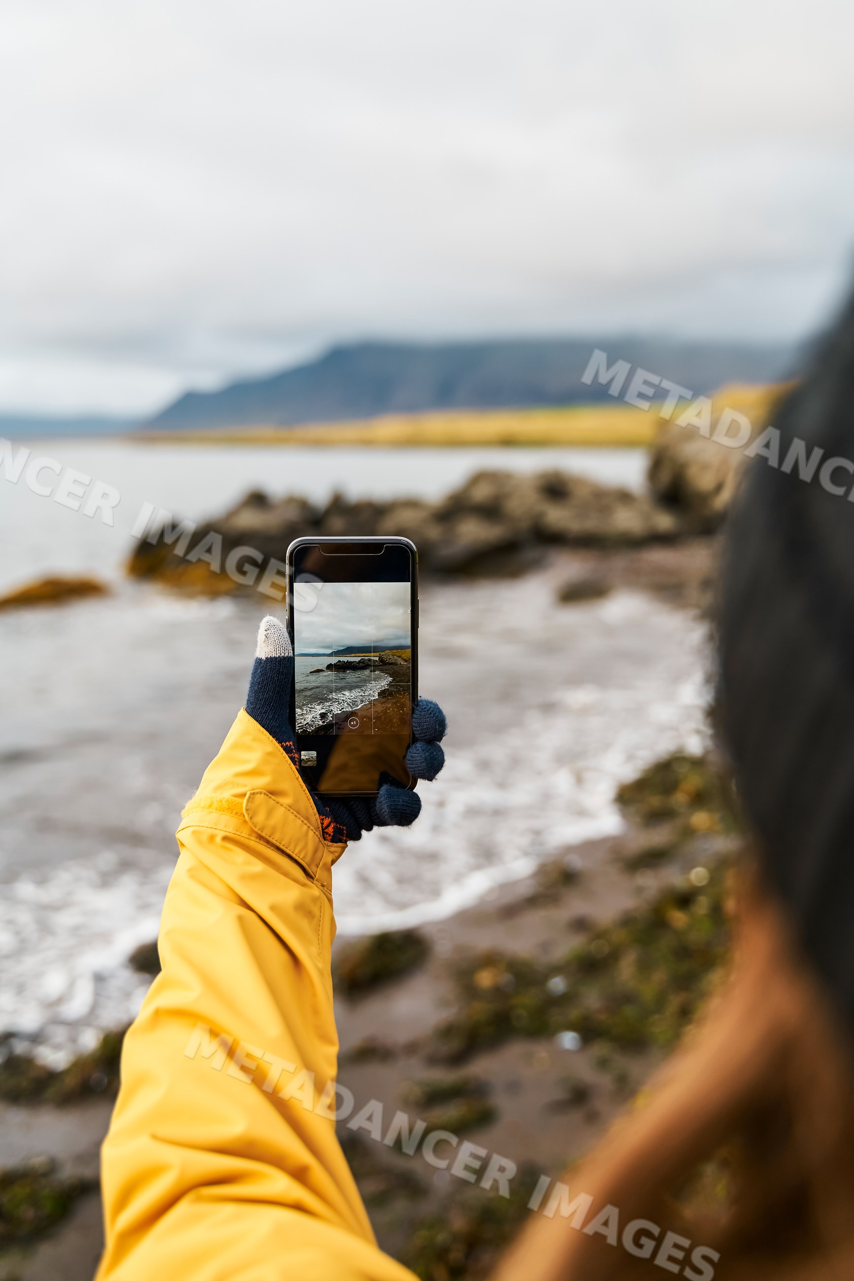 White Person taking photo of rocky coastline and sea on Iceland shore