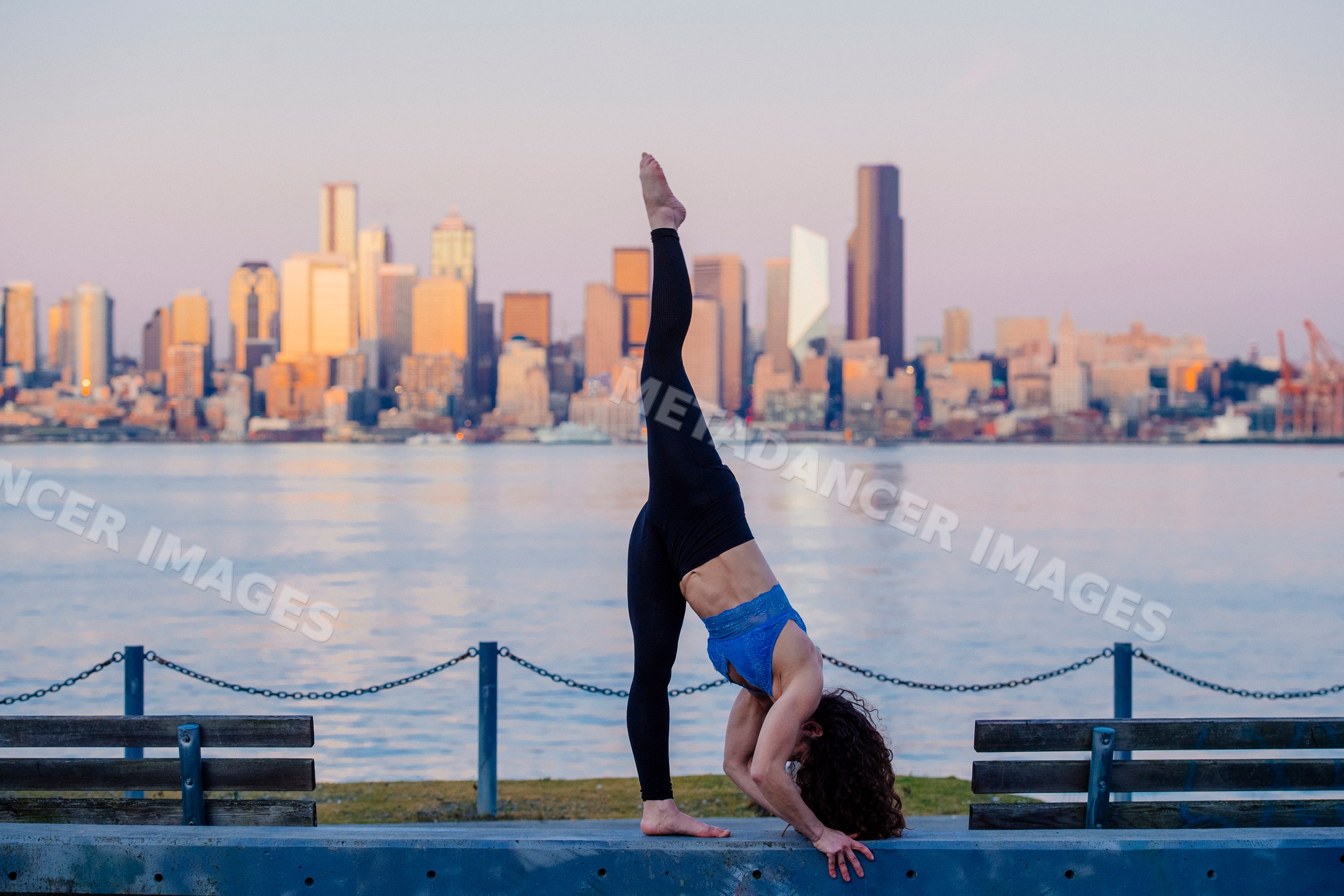 White woman practicing yoga stretch by Seattle waterfront at sunset