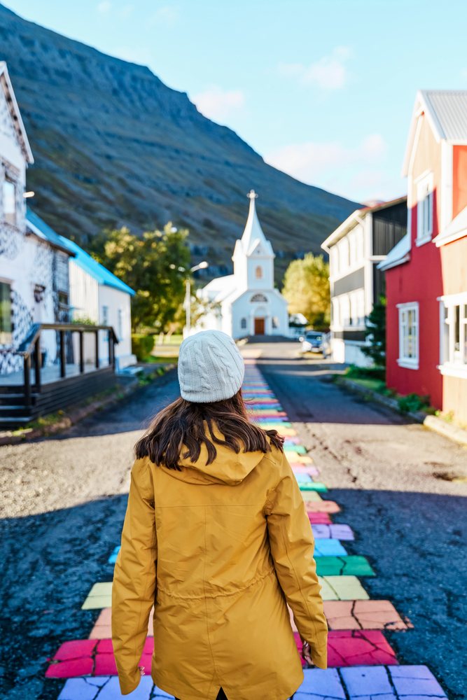 A woman walks along a colorful street path toward a white church