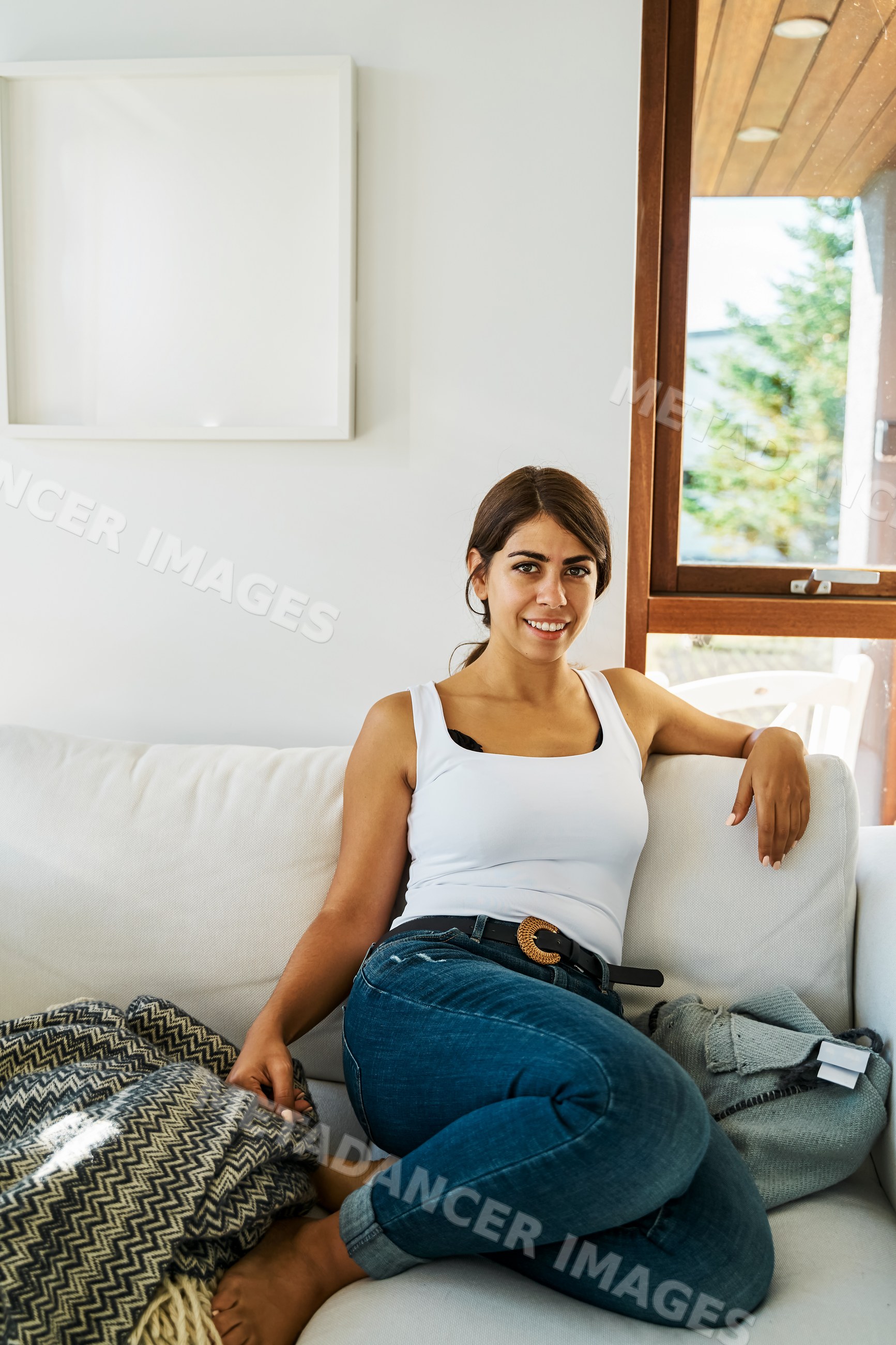 A woman sitting relaxed on a white sofa near a window in Iceland