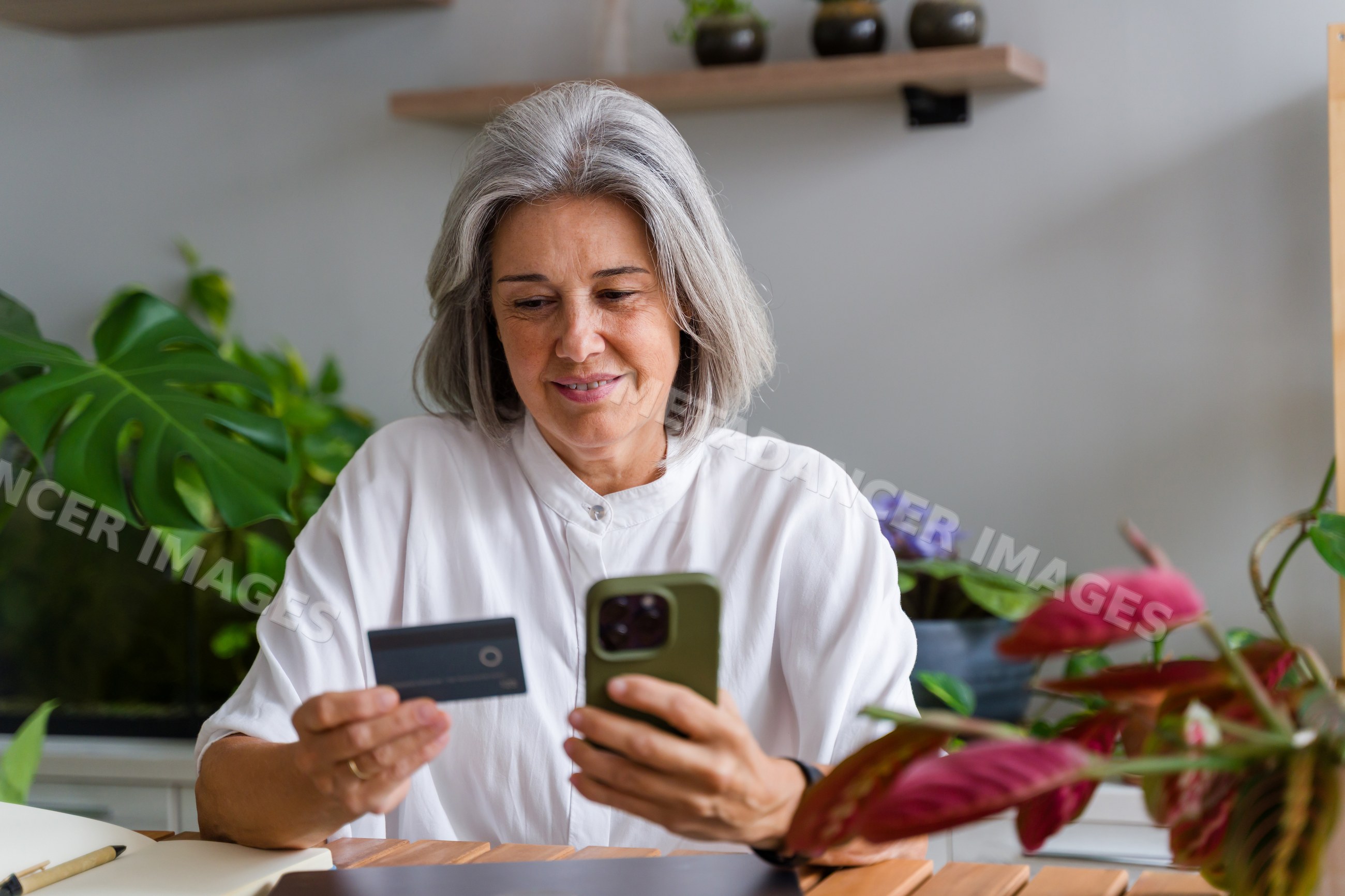 Mature white woman completing an online payment via smartphone