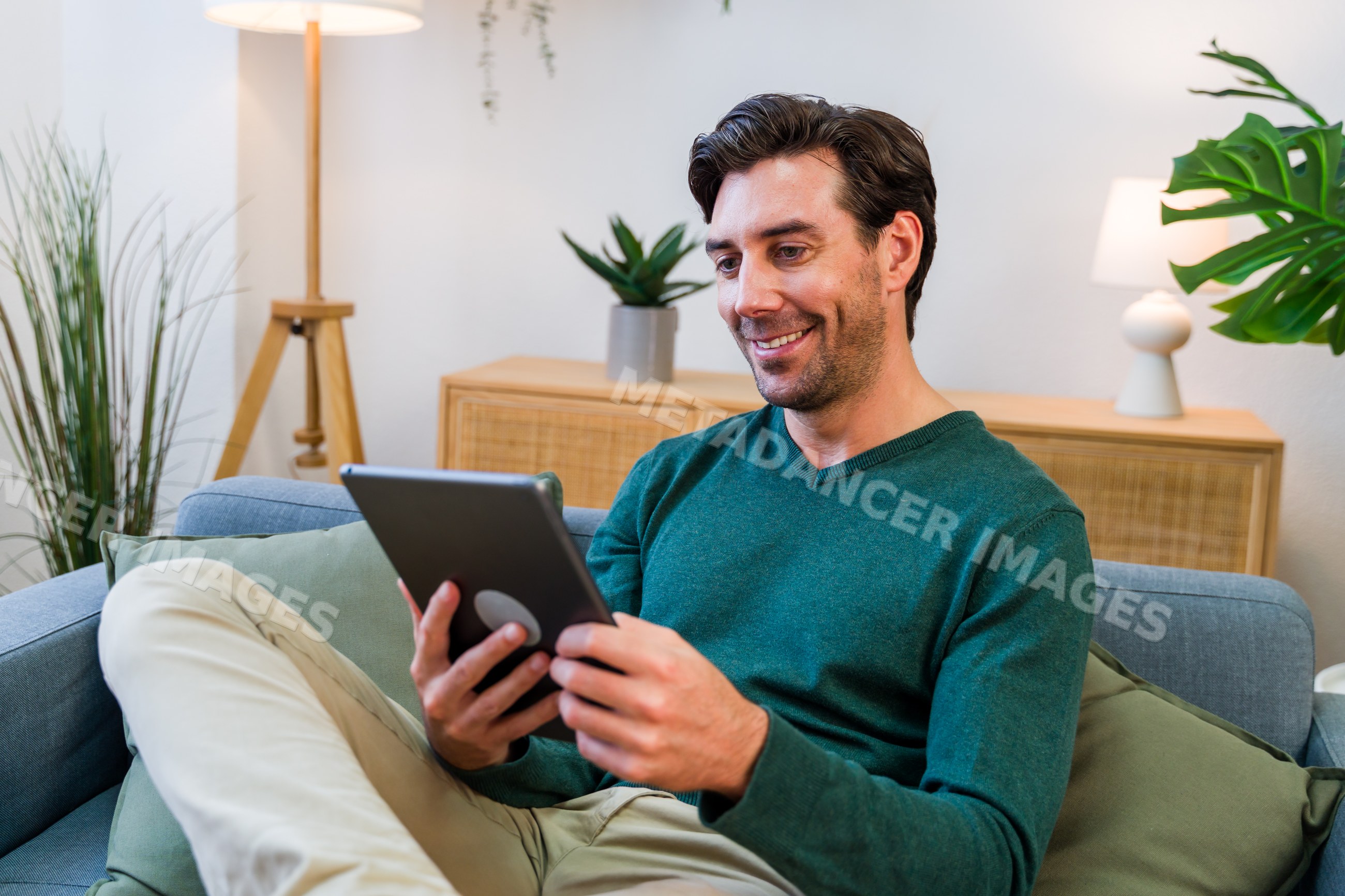 White man using tablet while sitting on couch in living room