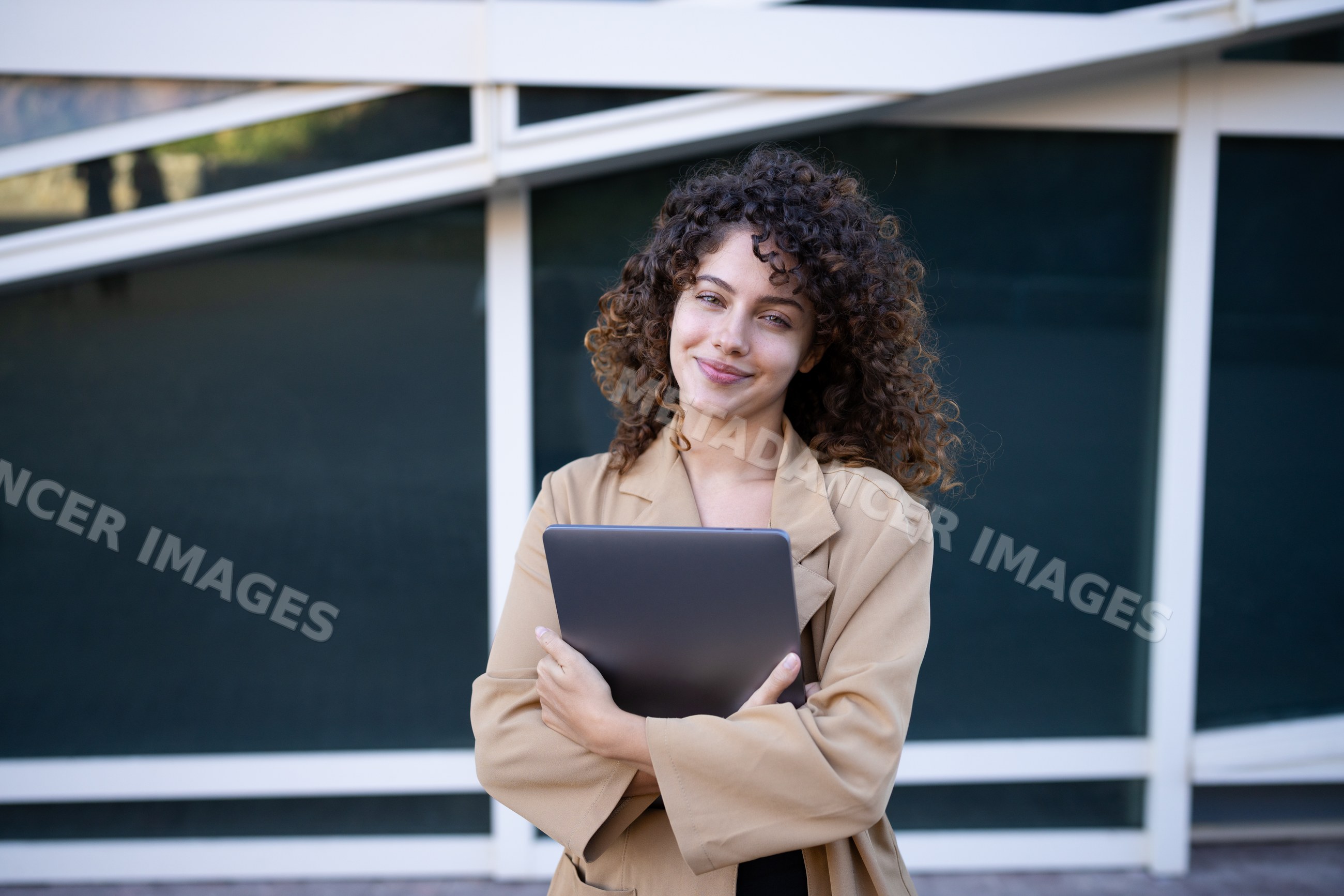 White woman holding tablet outside modern building