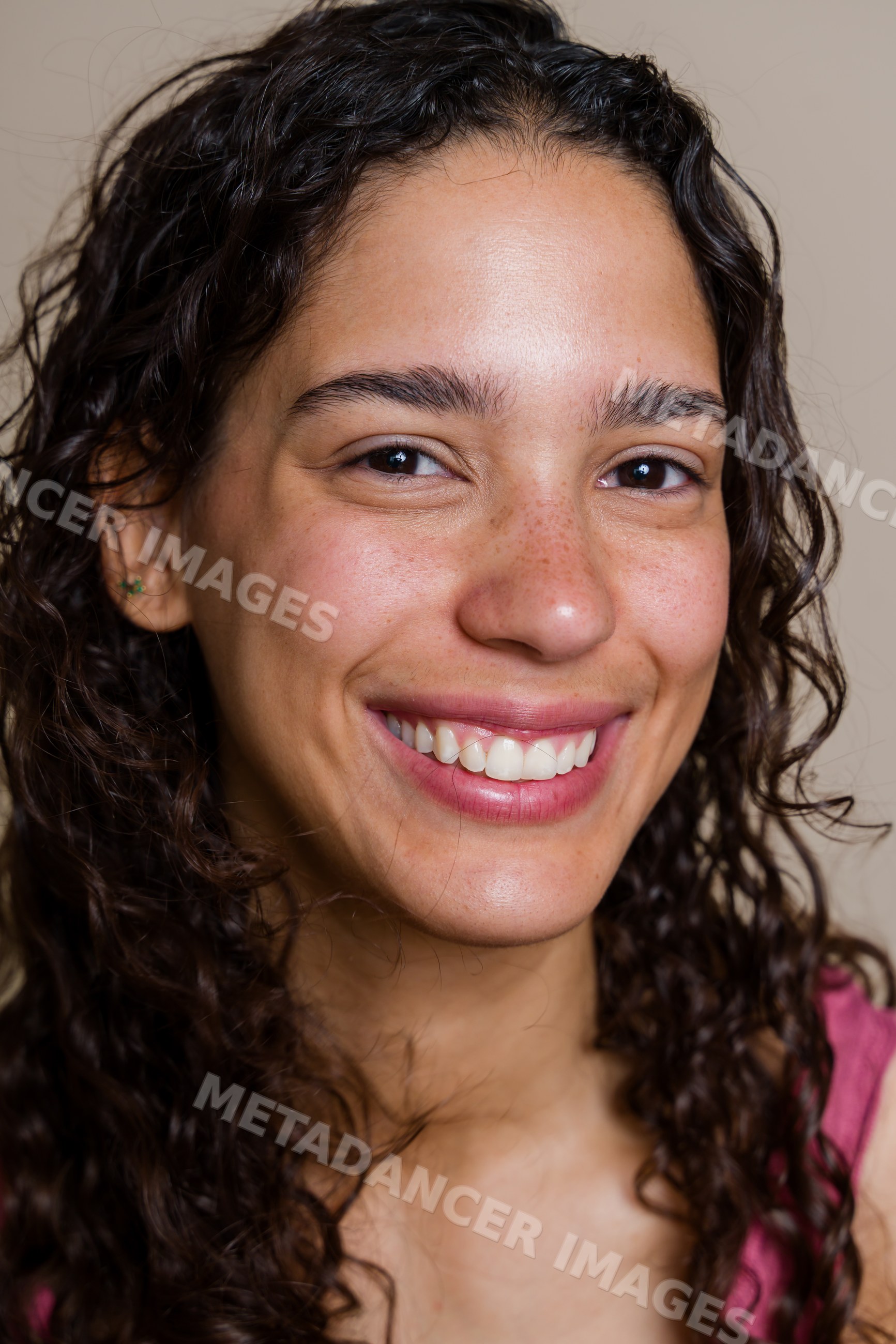 Hispanic woman smiling with curly hair and freckles