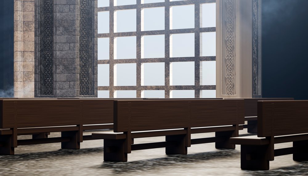 Empty wooden benches inside a church with stone walls and large