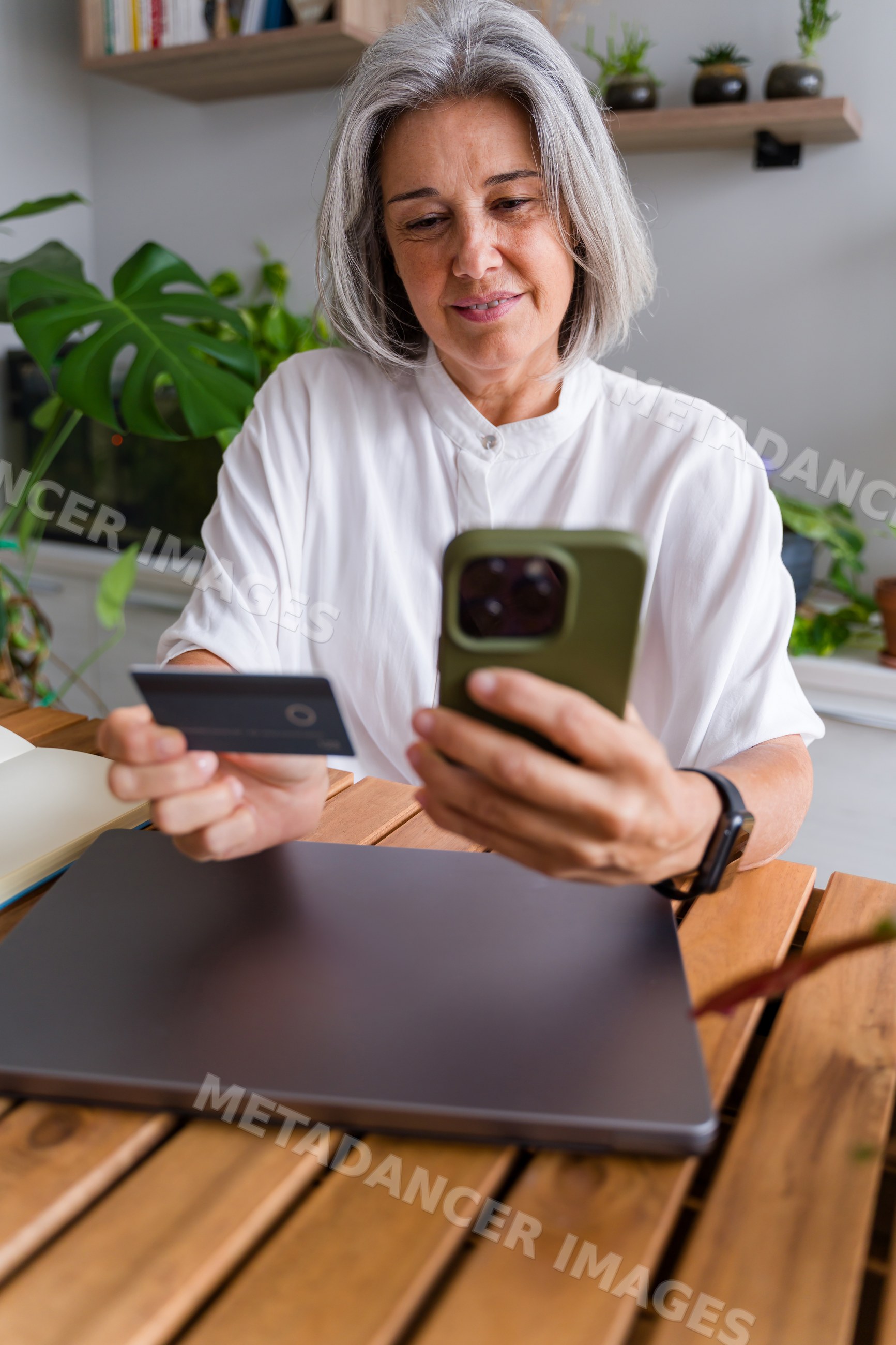 Mature white woman using smartphone and payment card for online