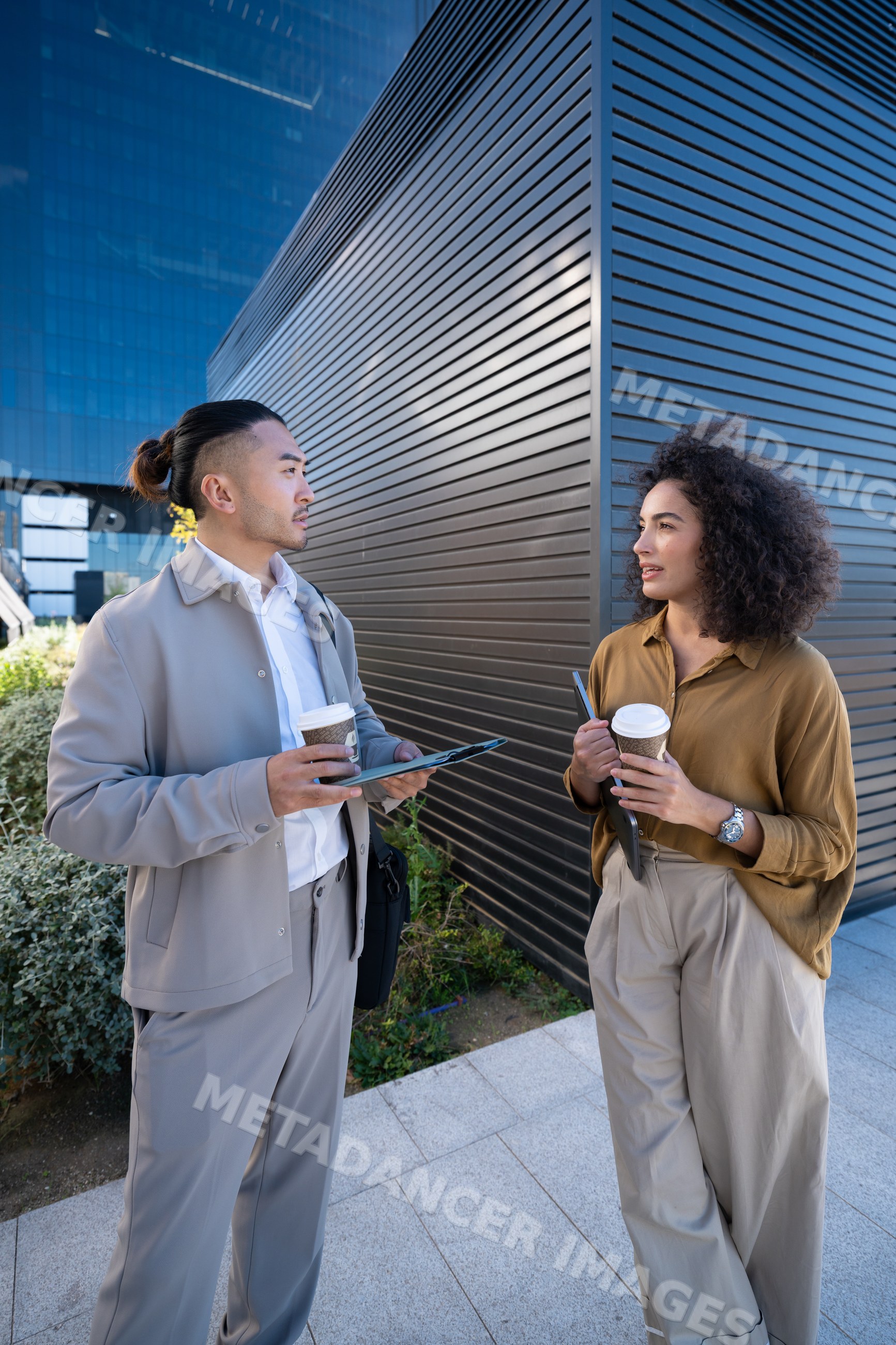 Two young professionals discussing outdoors near a modern building