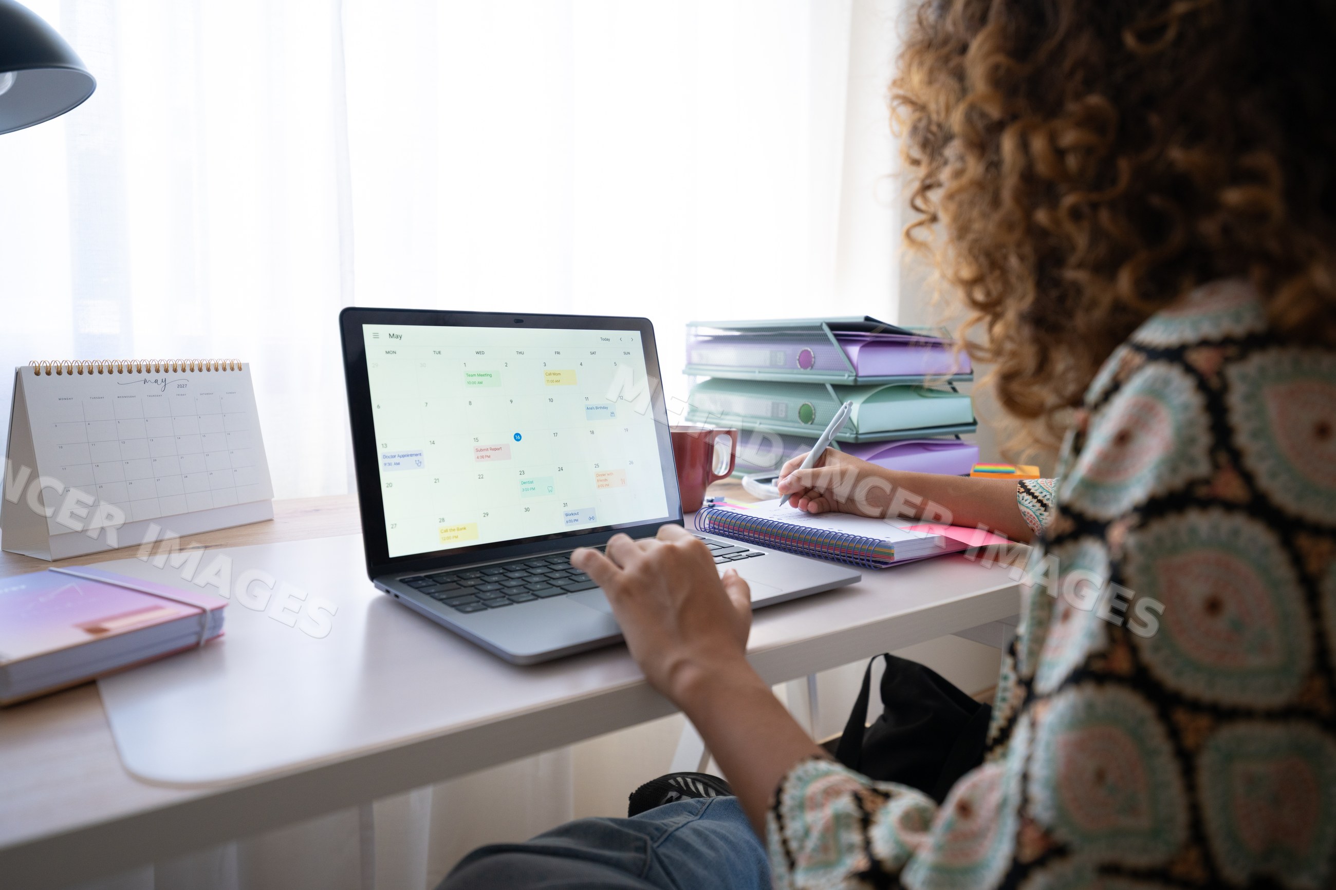 White woman working in home office at desk with laptop and calendar