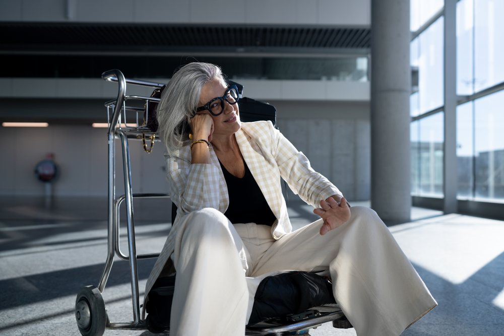 White woman sitting on luggage cart in Madrid airport terminal