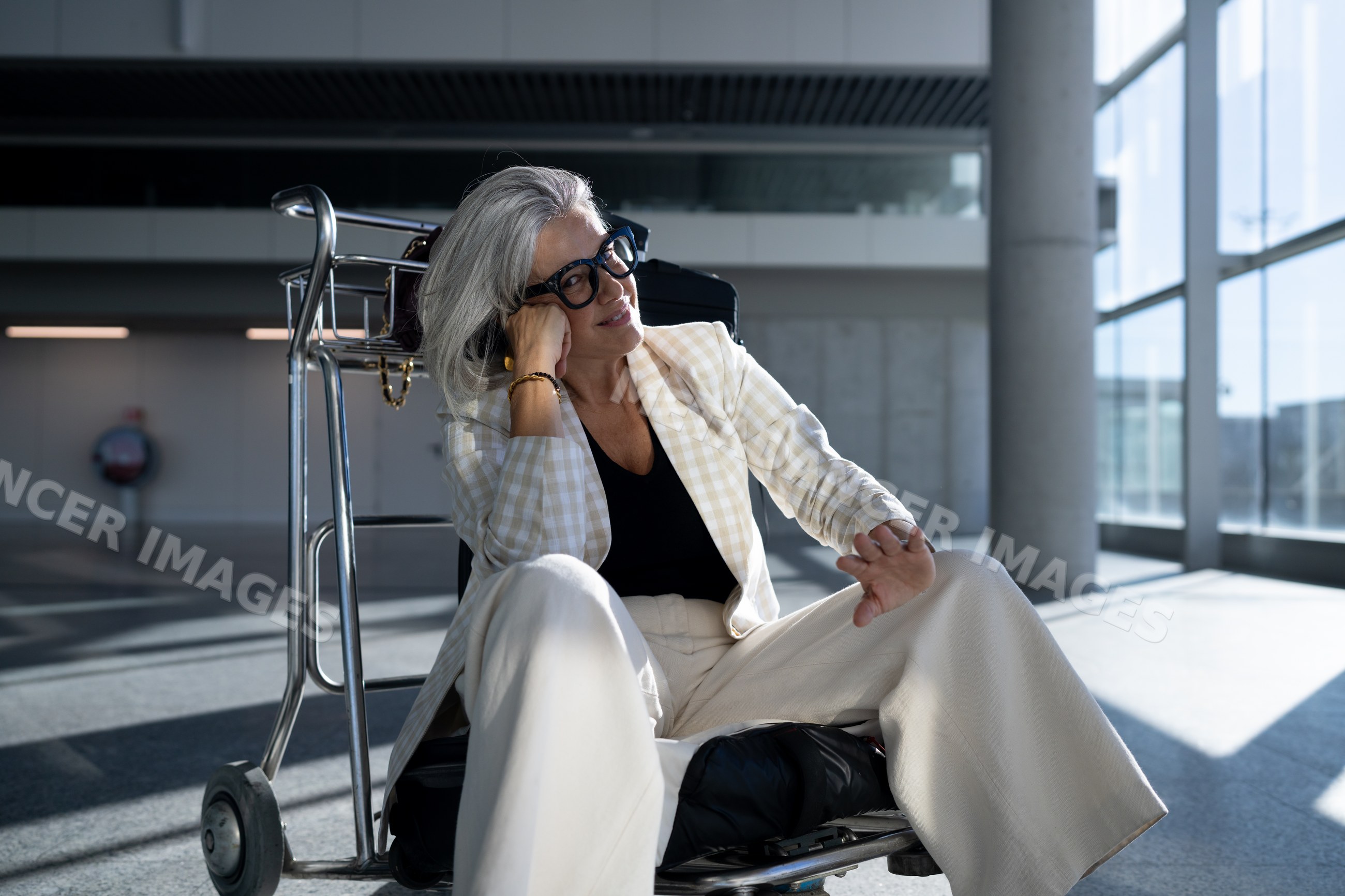 White woman sitting on luggage cart in Madrid airport terminal