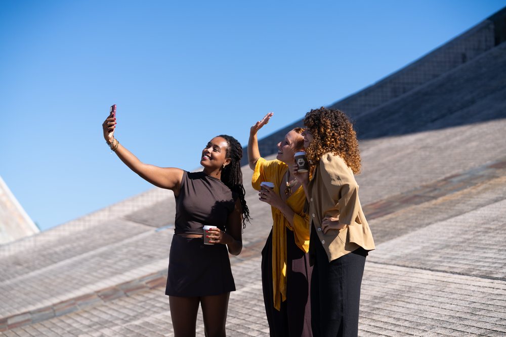 African American and white women taking selfie outdoors with blue sky