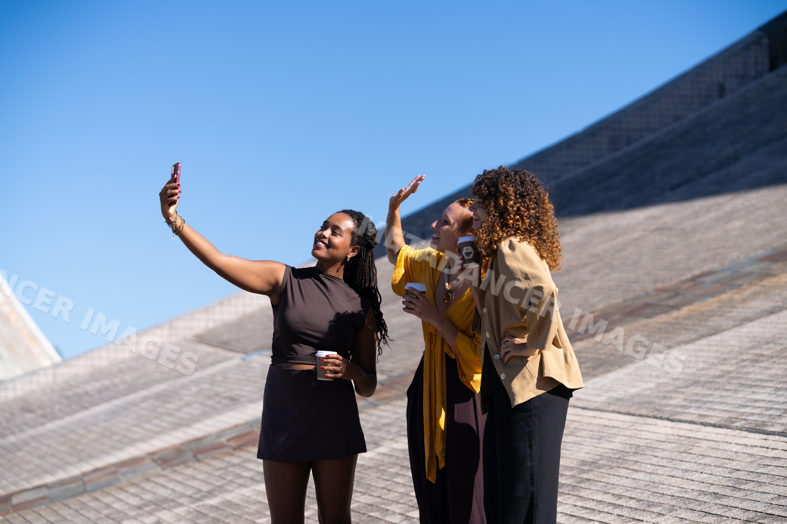 African American and white women taking selfie outdoors with blue sky