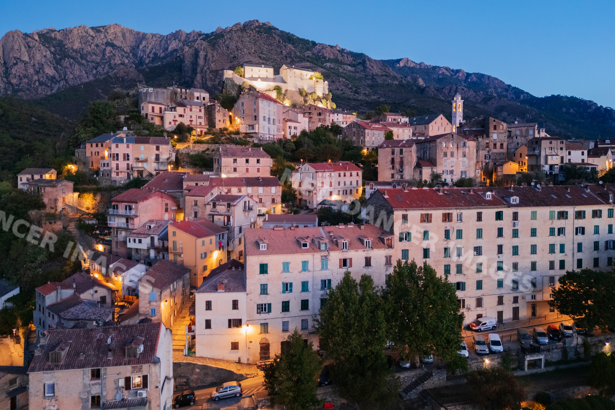 Town of corté on hillside at Dawn with illuminated fortress