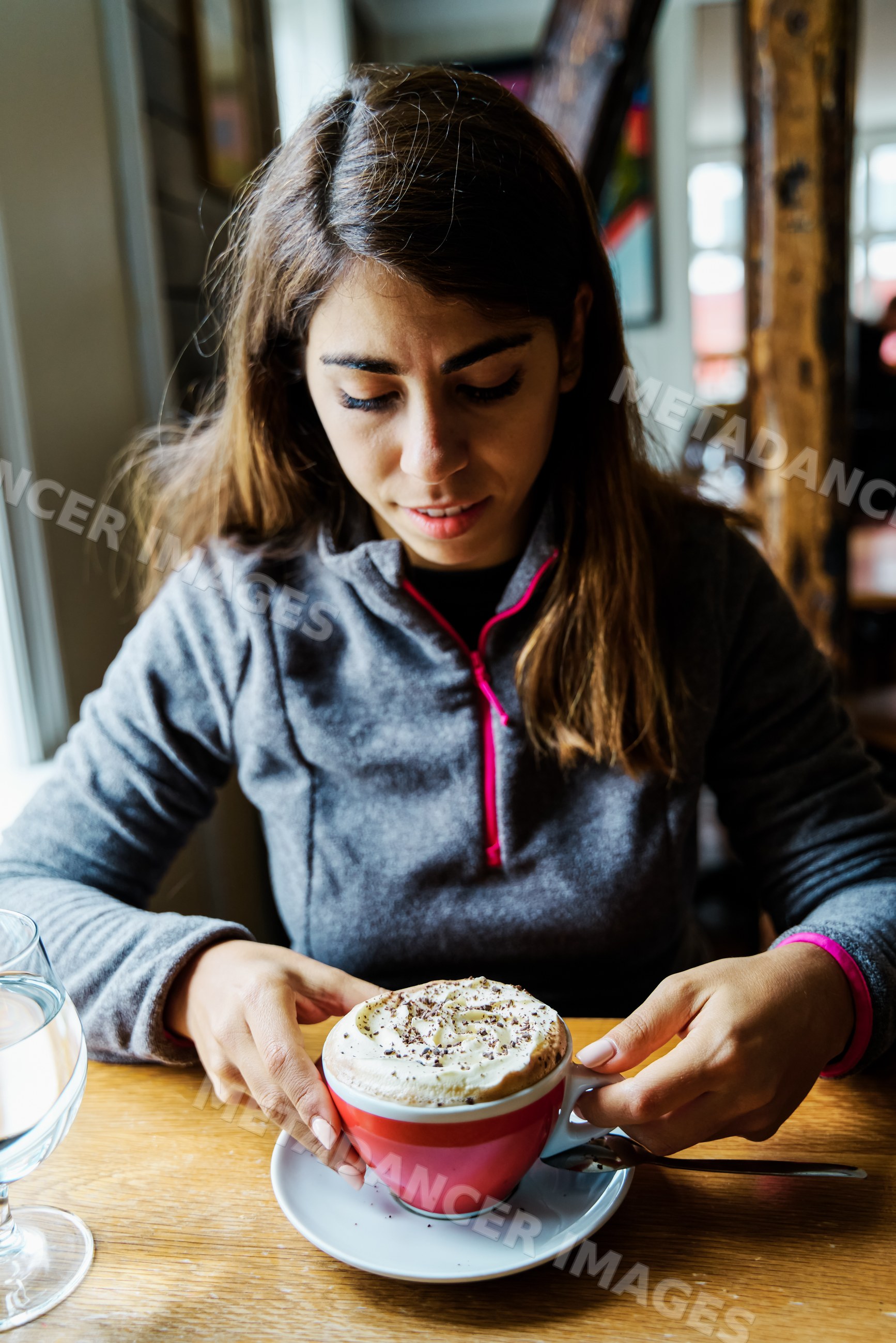 A white woman holds a cup of whipped cream coffee in a cafe in Iceland