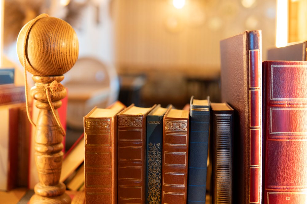 Antique leather-bound books displayed with a wooden spindle