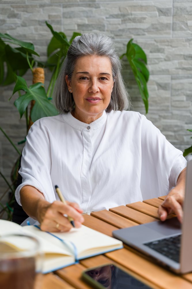Mature gray-haired white woman writing