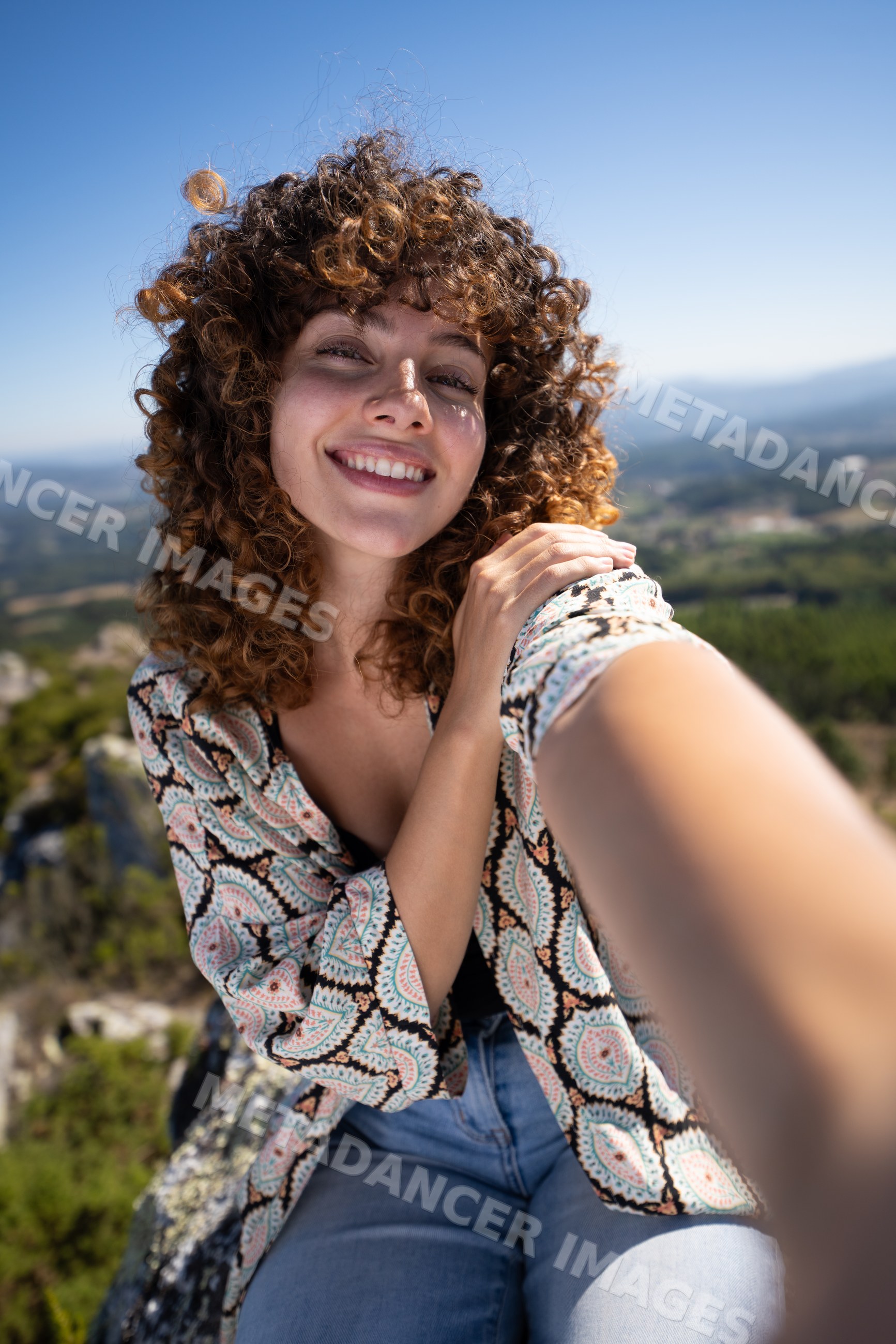 White woman taking smiling selfie with scenic Pico Sacro mountainous
