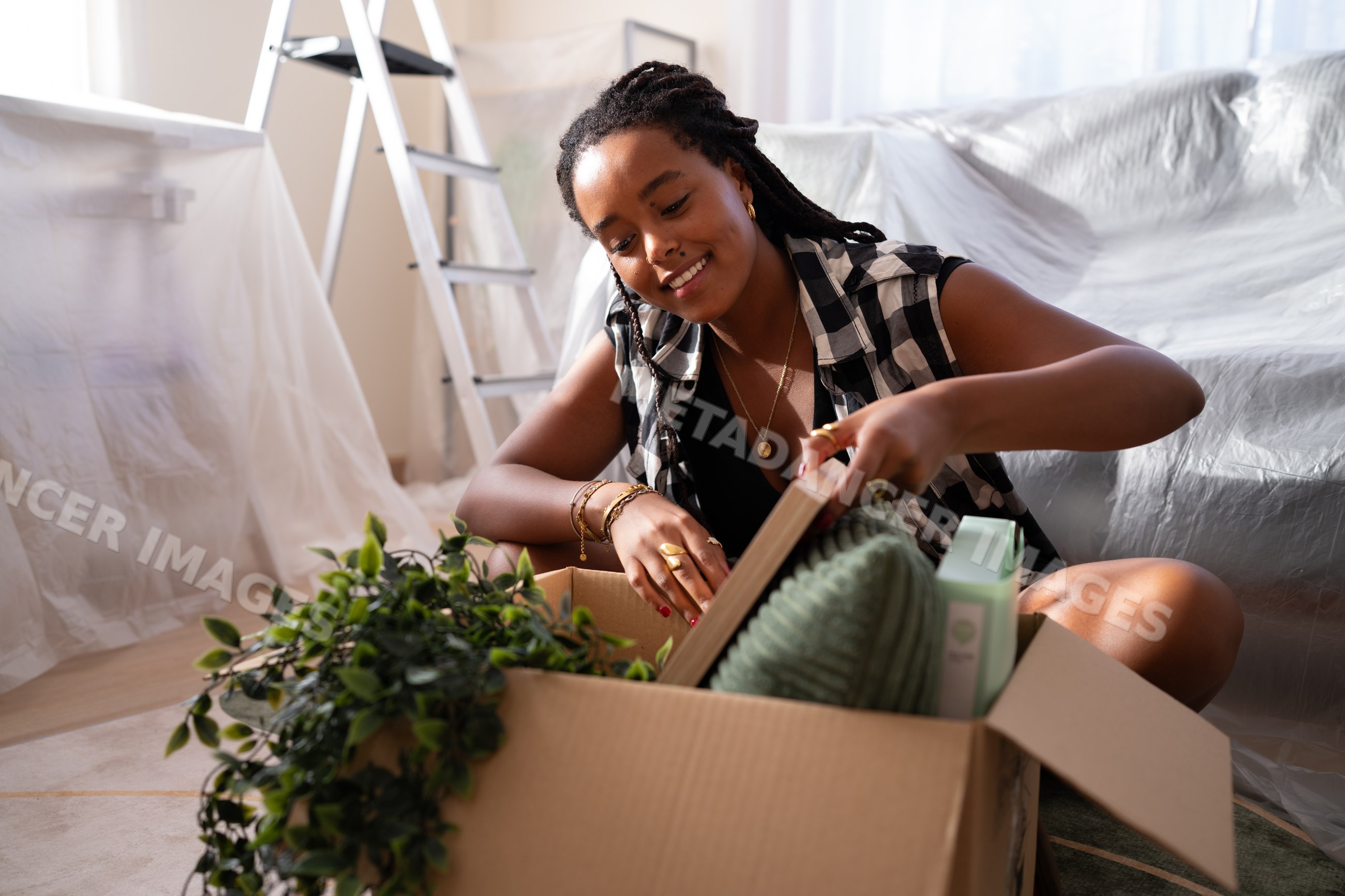 A African American woman unpacks home items in a room while moving